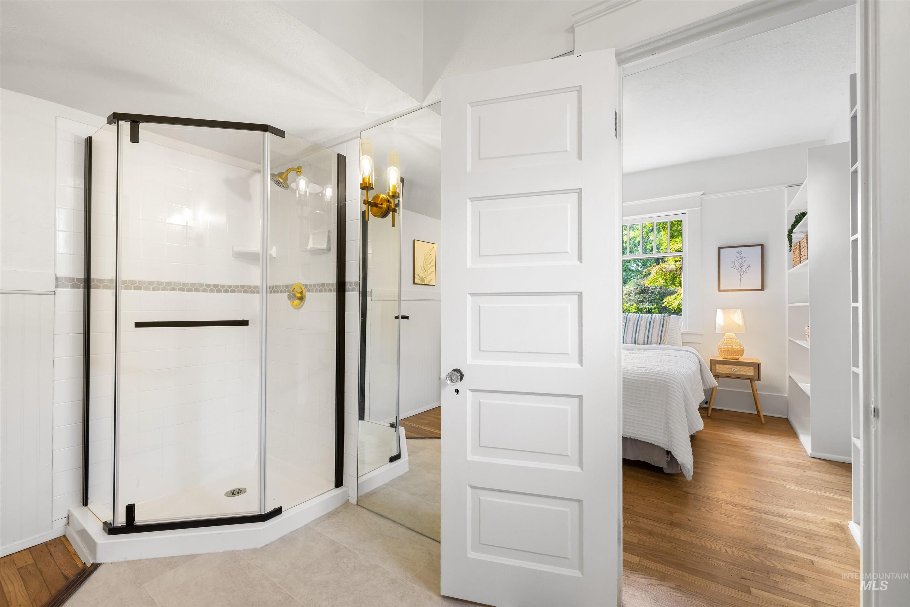 Full bath with a stall shower, light wood finished floors, and ensuite bath