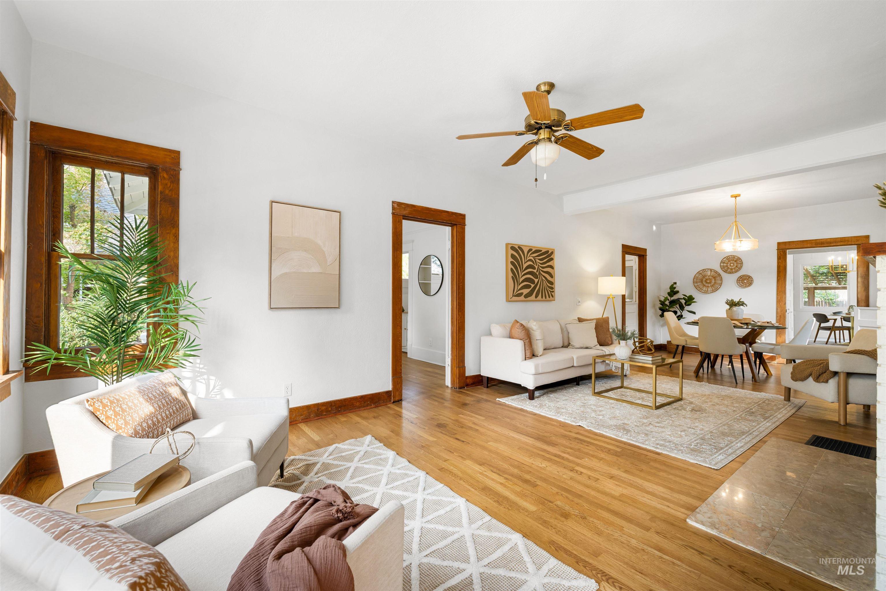 Living area featuring light wood finished floors, ceiling fan, and beam ceiling