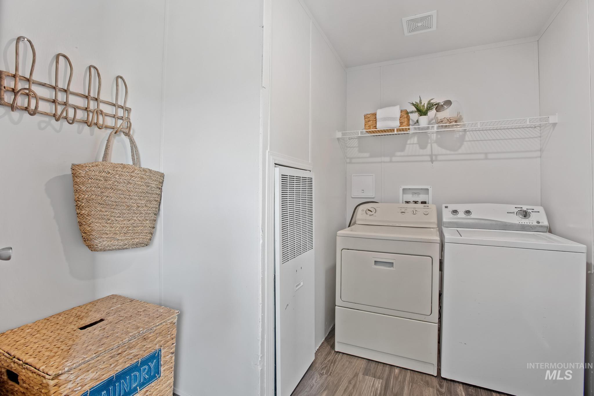 Washroom with wood finished floors, a heating unit, and separate washer and dryer