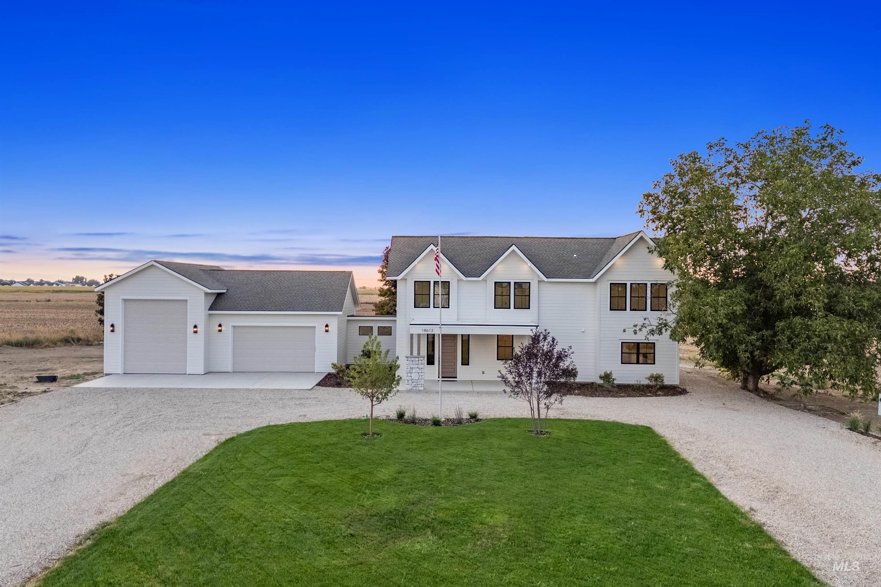 Modern farmhouse style home with gravel driveway, a porch, a front lawn, and an attached garage