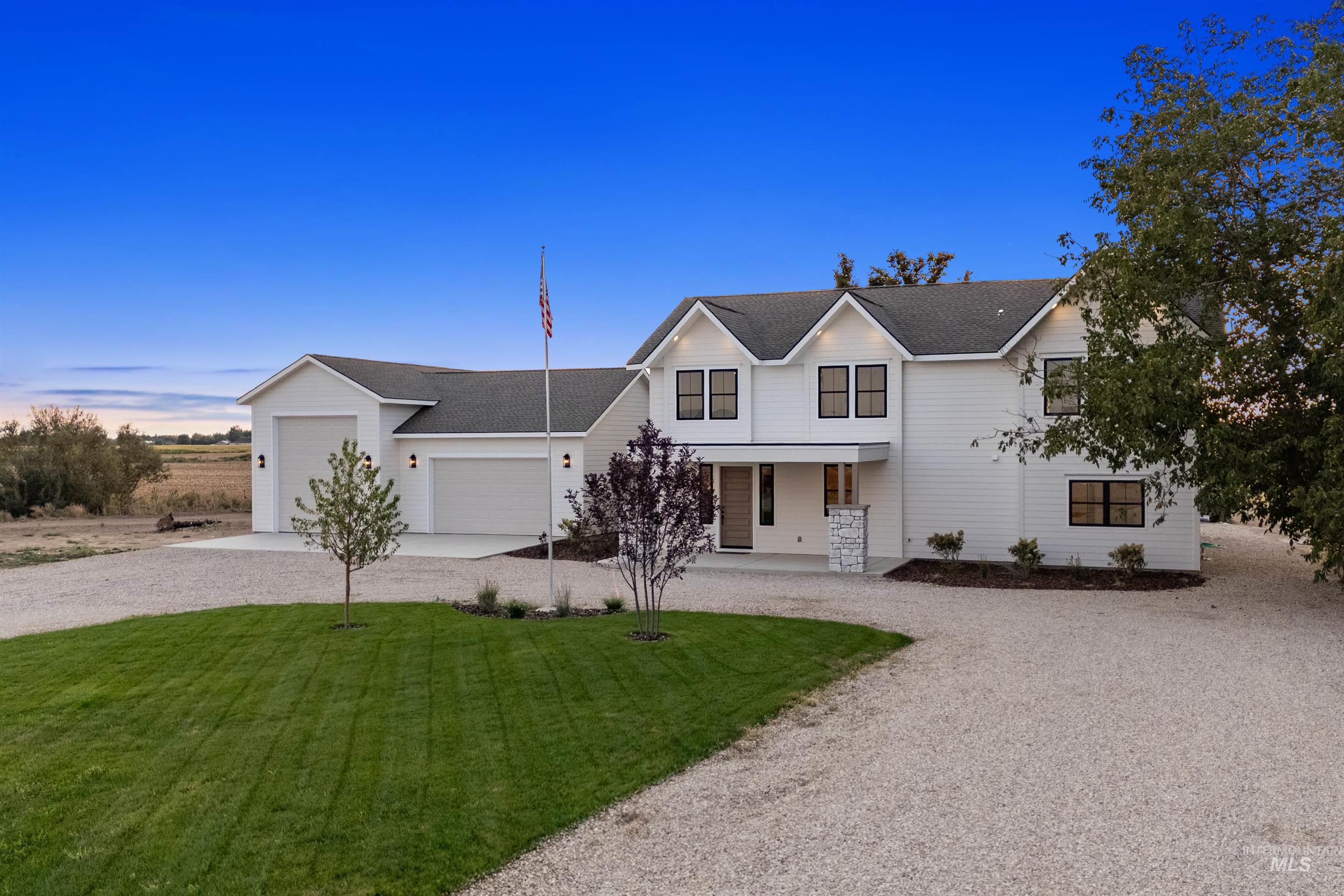 Modern farmhouse with gravel driveway, a porch, a garage, a front lawn, and a shingled roof