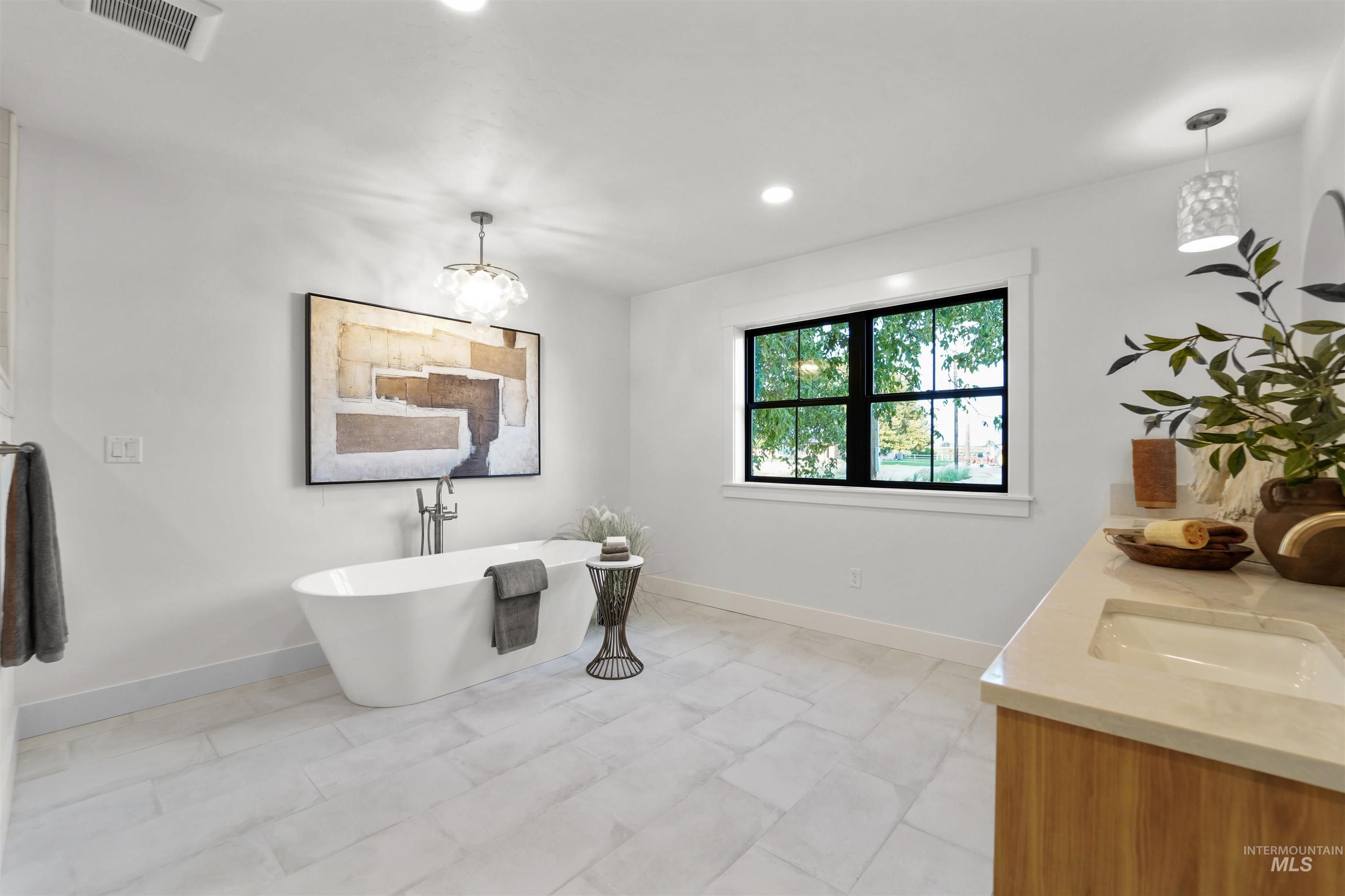 Full bathroom featuring a freestanding tub, double vanity, recessed lighting, and a chandelier