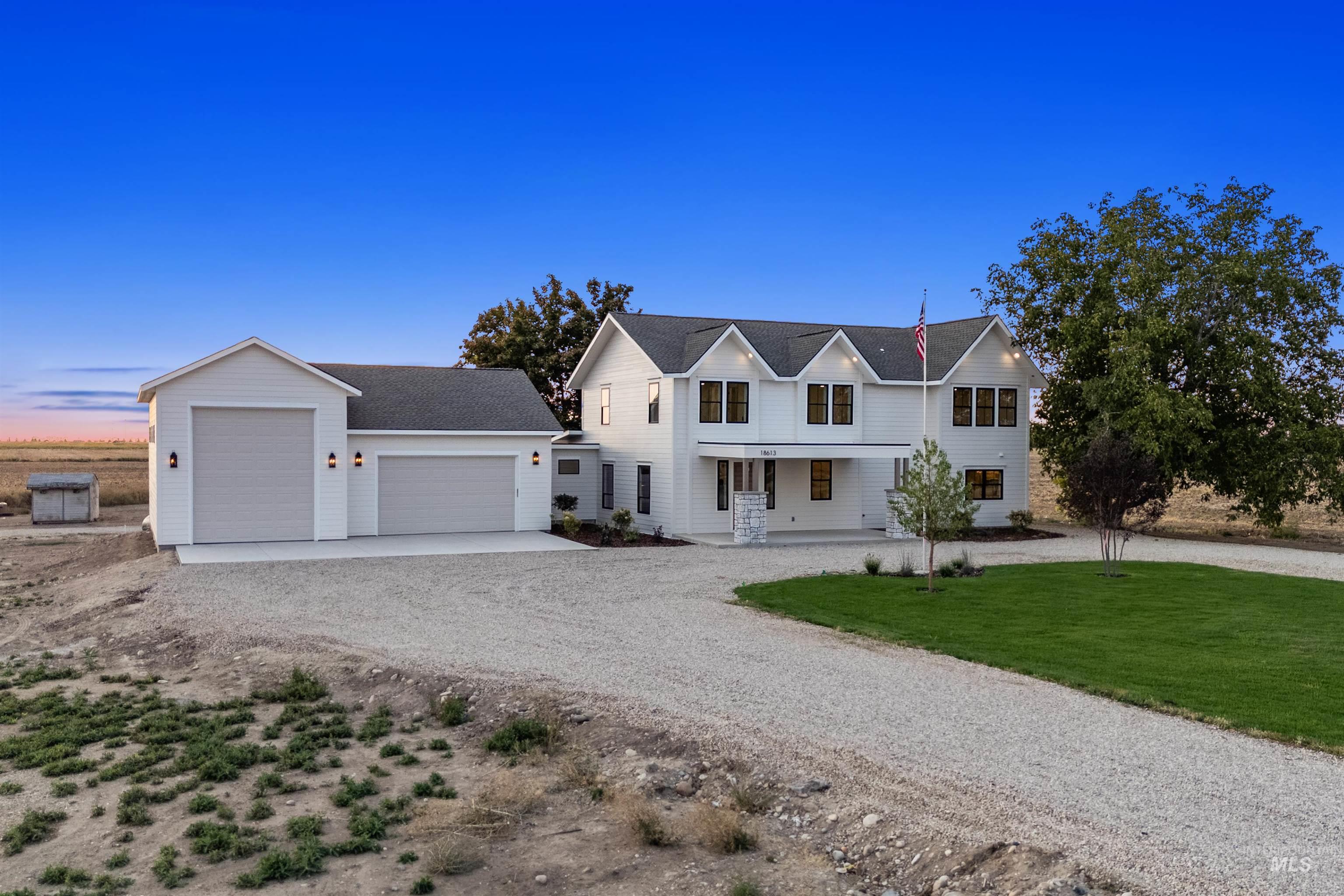 Modern farmhouse style home featuring covered porch, driveway, an outdoor structure, a shingled roof, and a front lawn