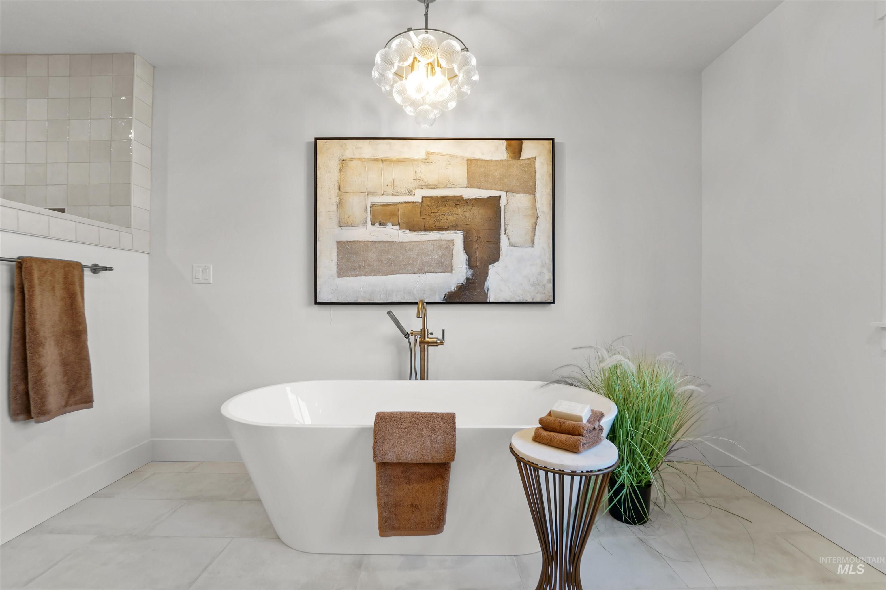 Bathroom featuring a soaking tub, tile patterned flooring, and a chandelier