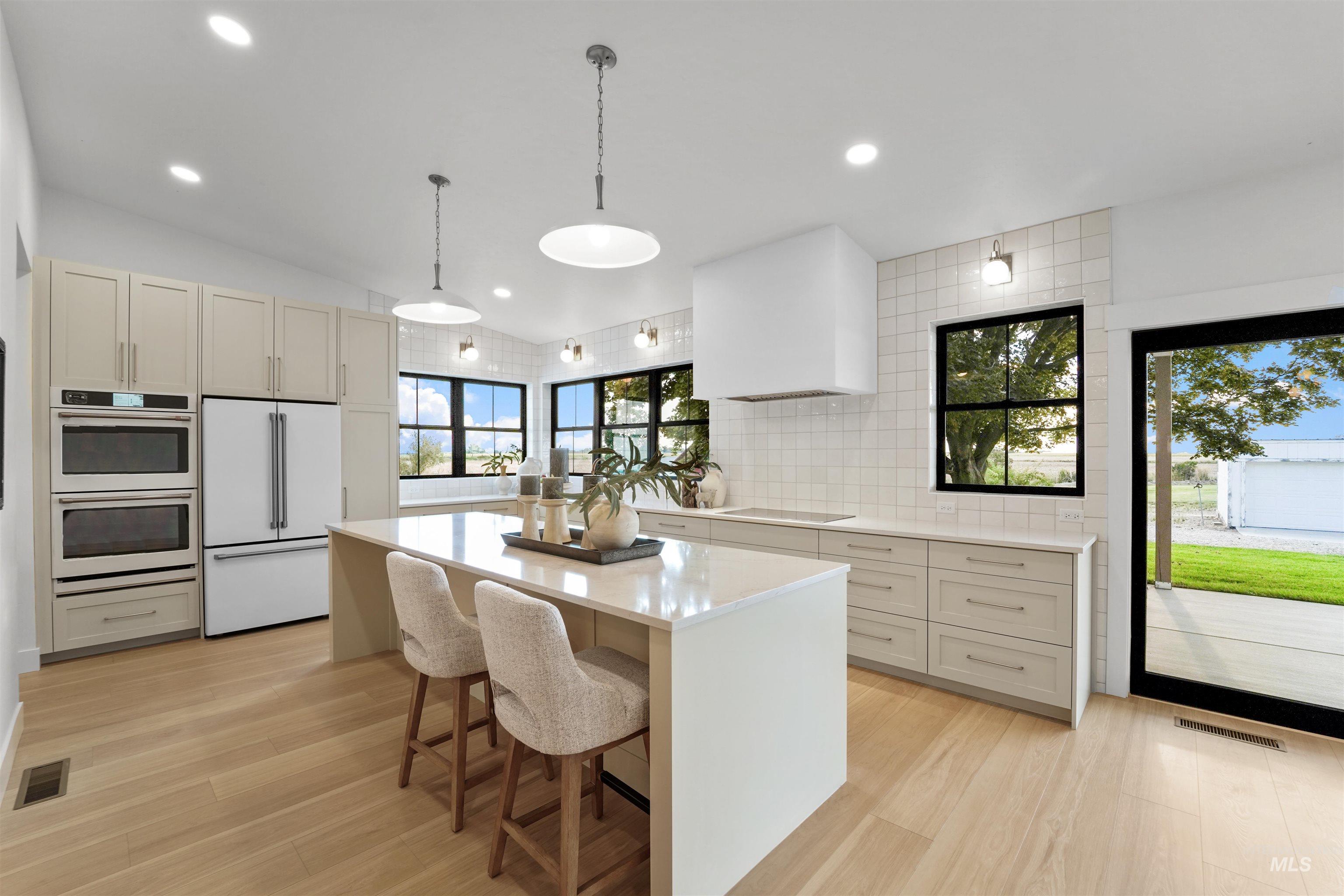 Kitchen with white appliances, a kitchen island, pendant lighting, a breakfast bar, and light wood-style flooring