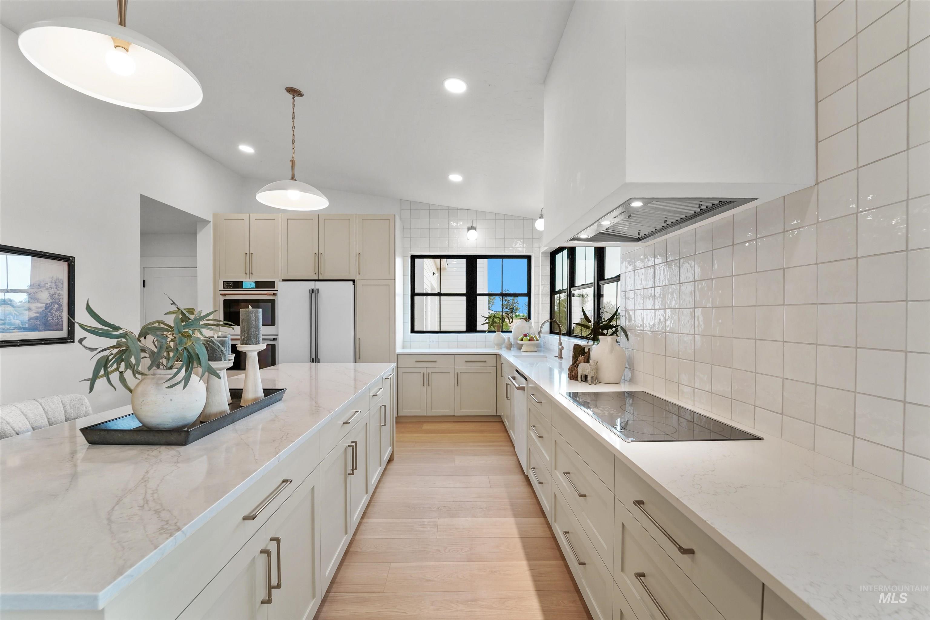 Kitchen featuring a kitchen island, light stone countertops, light wood-type flooring, lofted ceiling, and decorative backsplash
