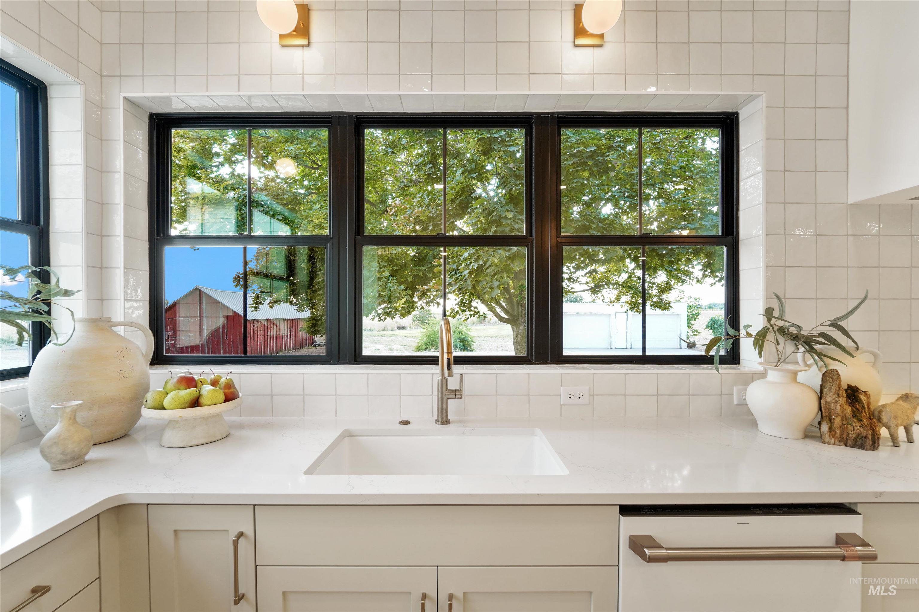 Kitchen with light stone countertops, plenty of natural light, and cream cabinets