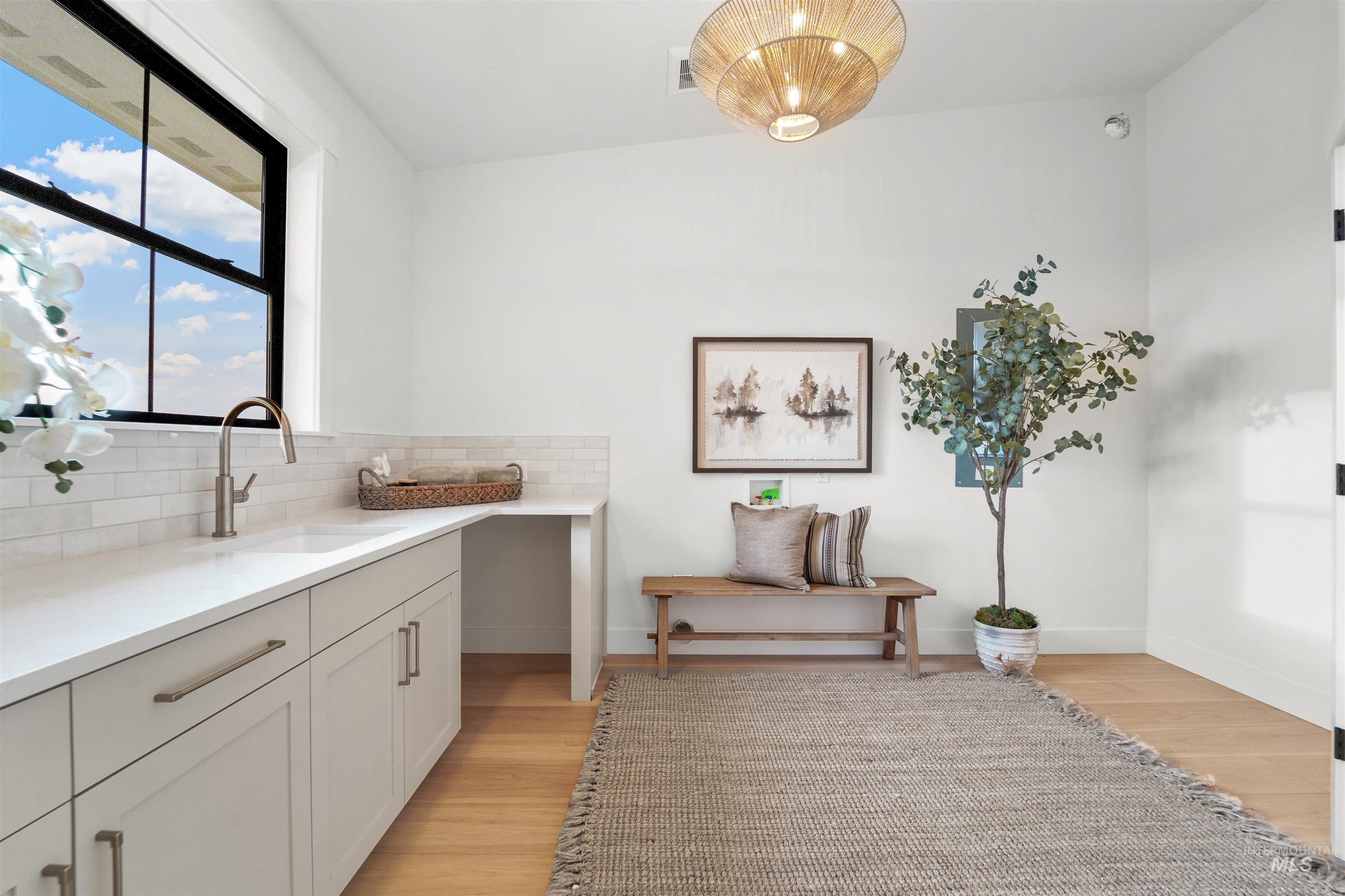 Kitchen featuring light wood-style flooring, tasteful backsplash, white cabinets, and light stone countertops