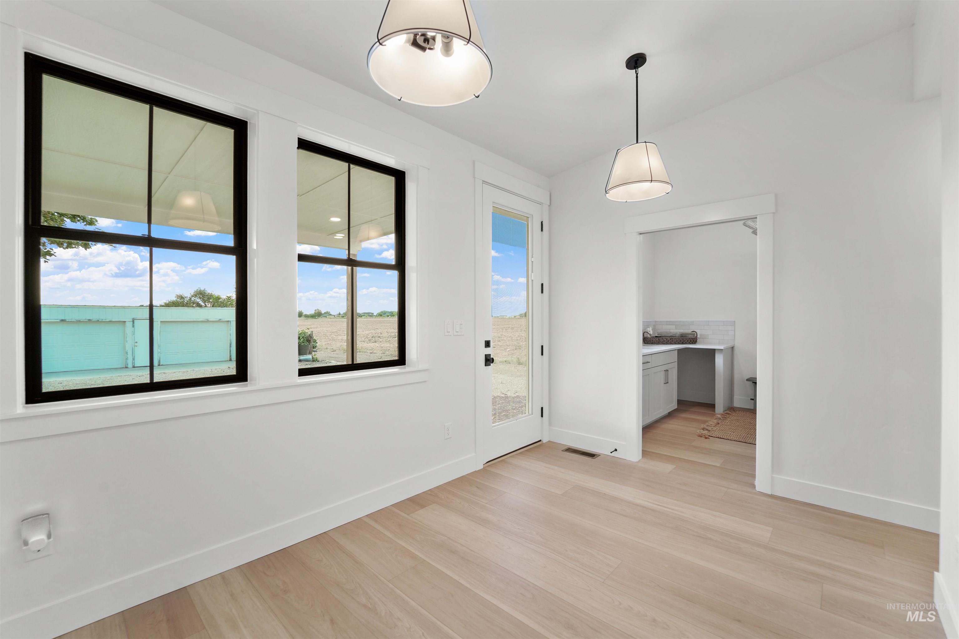 Unfurnished dining area with light wood-style floors, built in desk, and vaulted ceiling