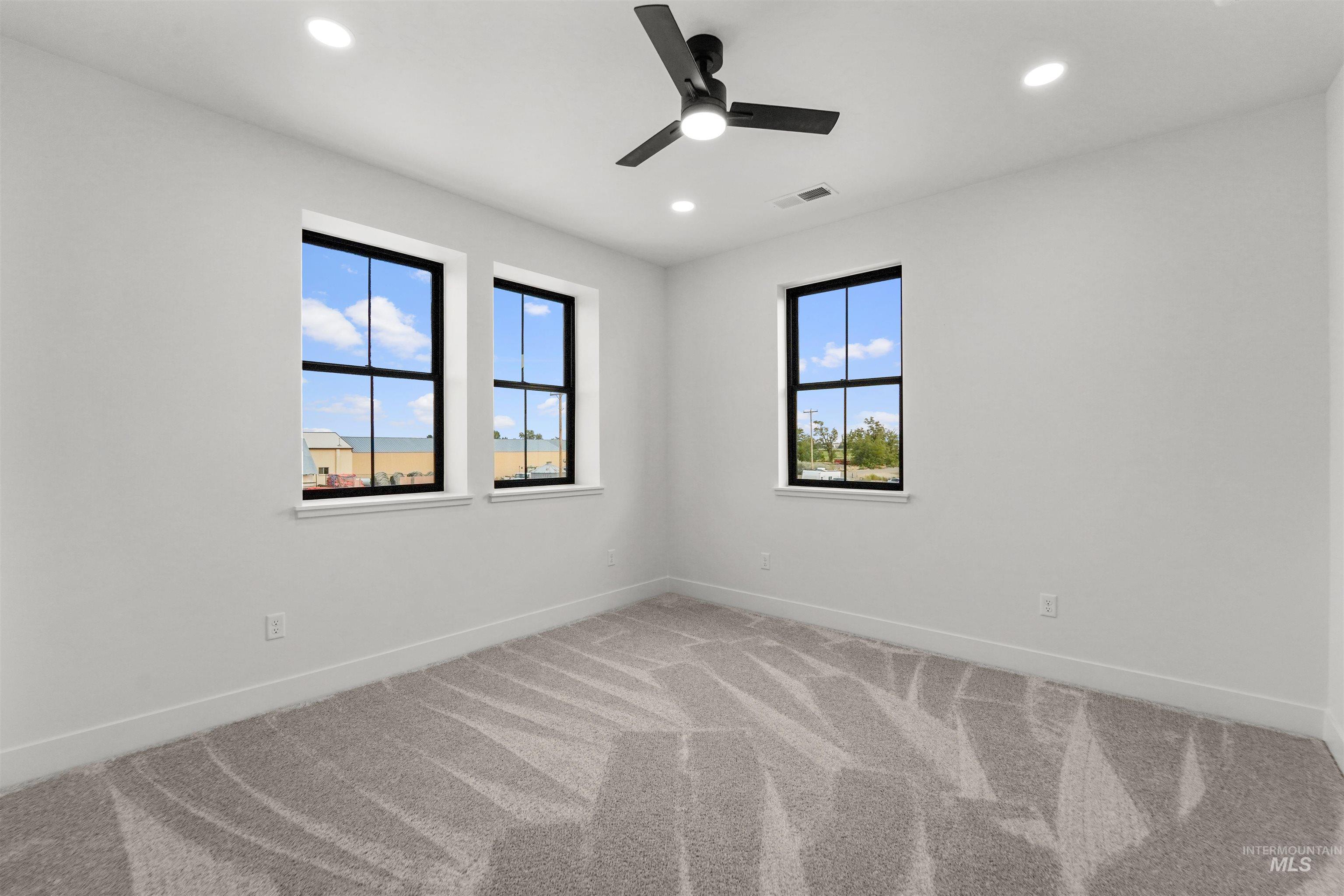 Unfurnished room featuring light colored carpet, healthy amount of natural light, recessed lighting, and a ceiling fan