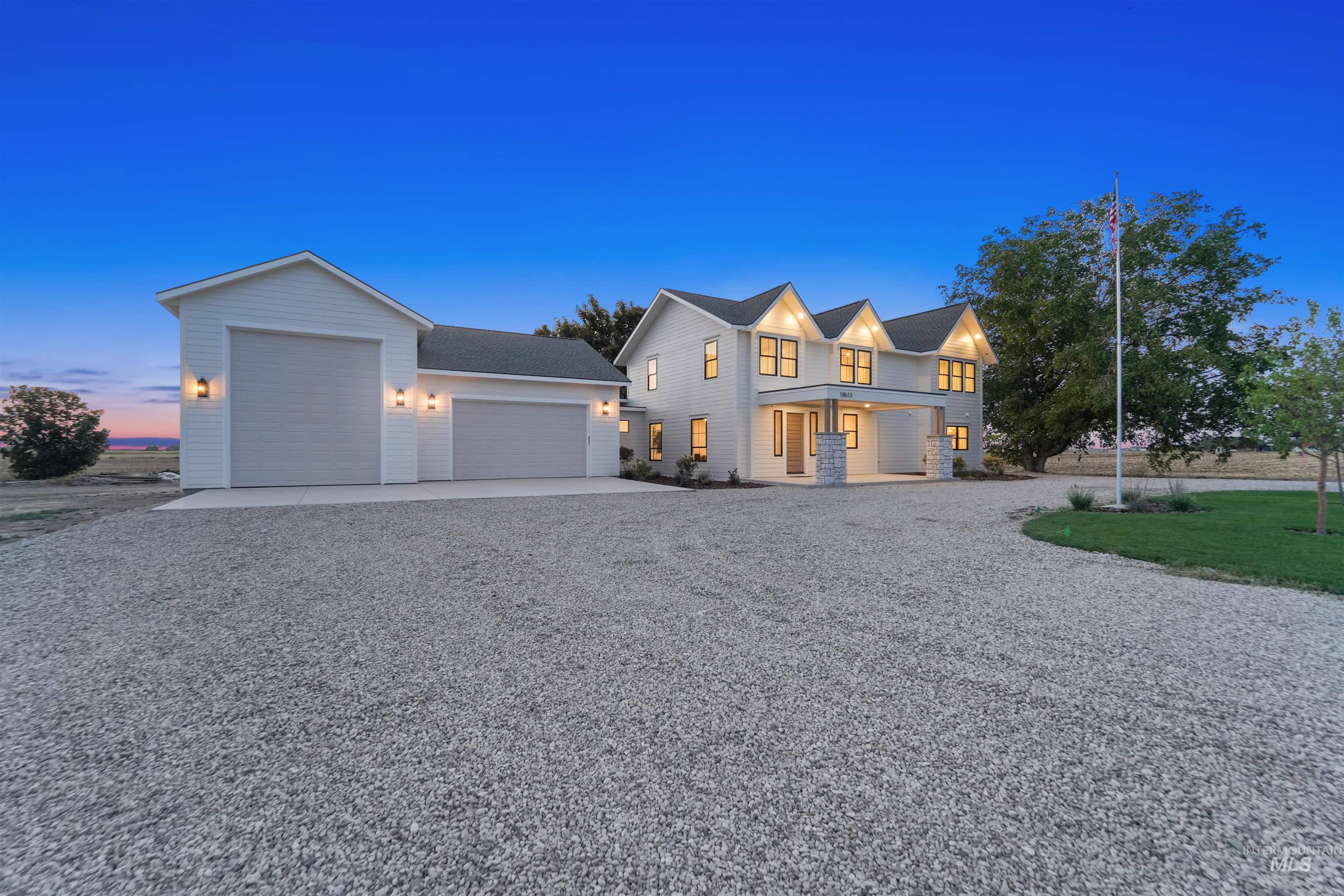 View of front of property featuring a garage, gravel driveway, and roof with shingles