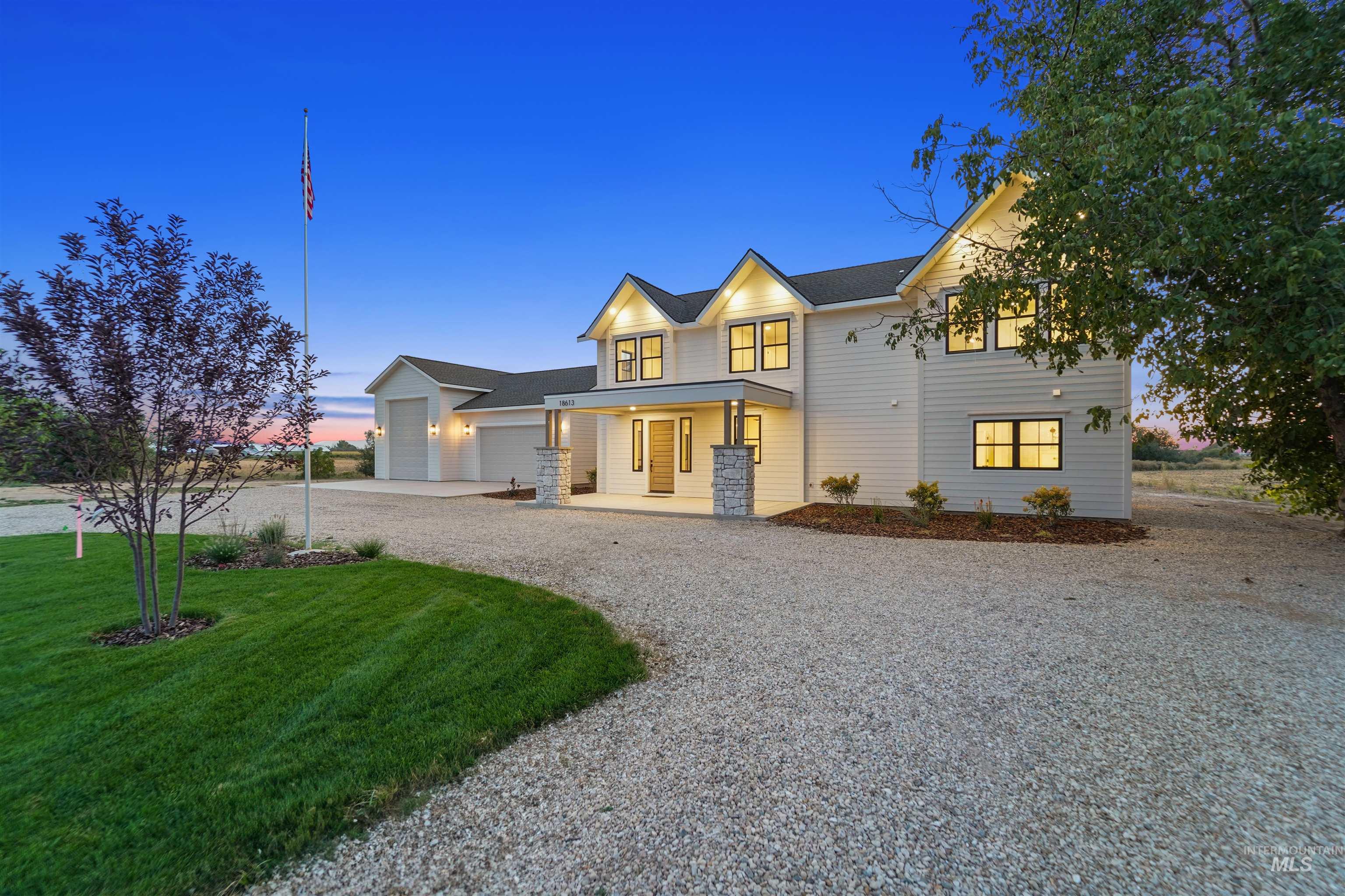 Modern farmhouse featuring covered porch, driveway, a garage, and a yard