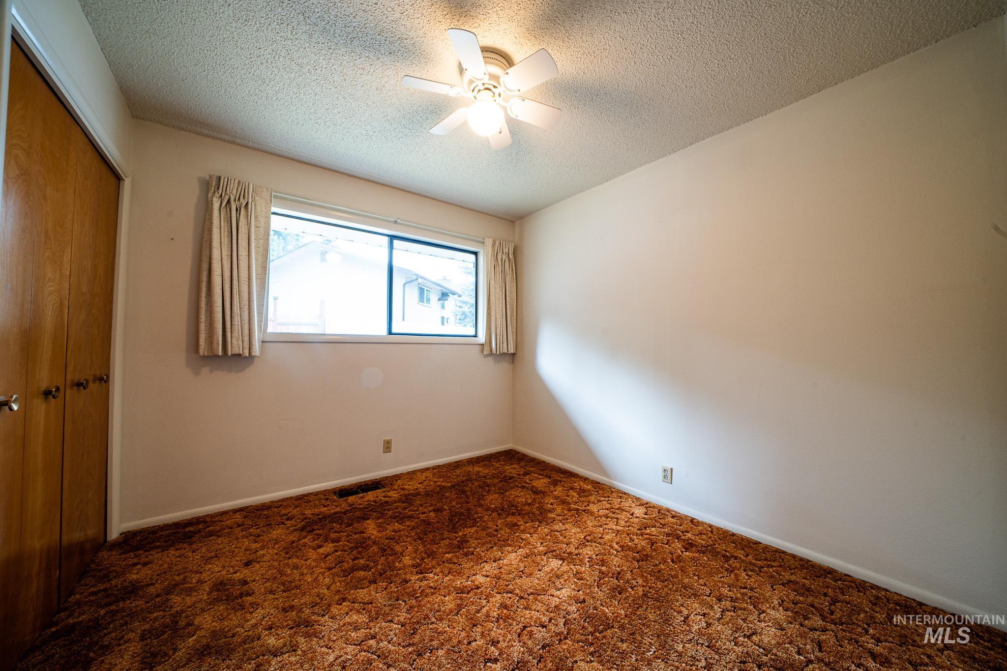 Spare room featuring carpet floors, a textured ceiling, and a ceiling fan