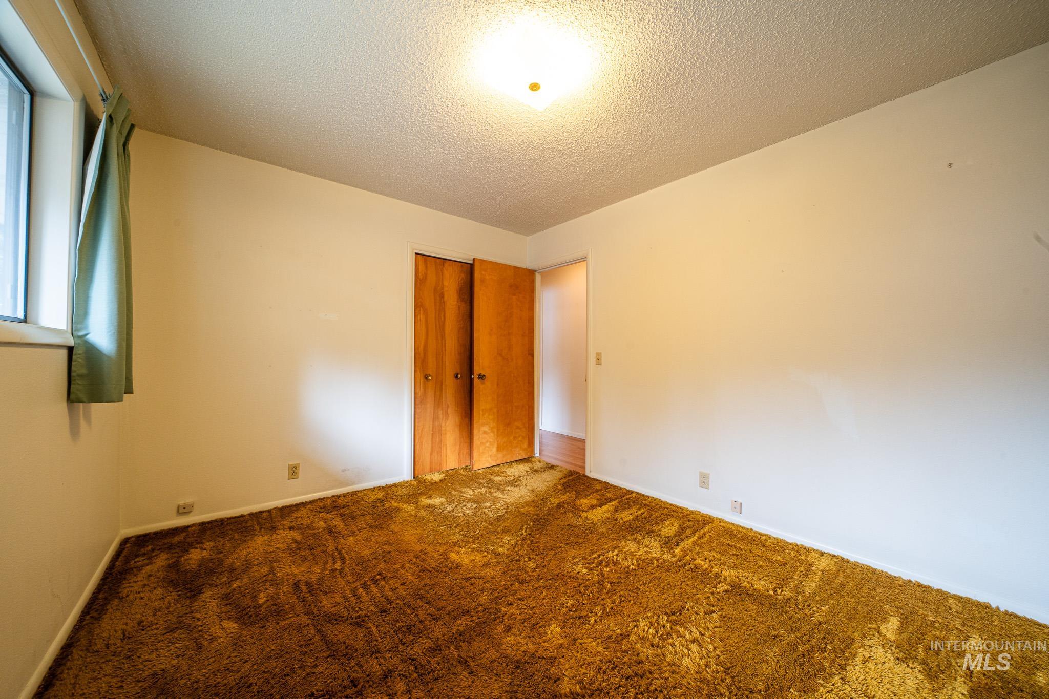 Unfurnished bedroom featuring a textured ceiling, carpet flooring, and a closet