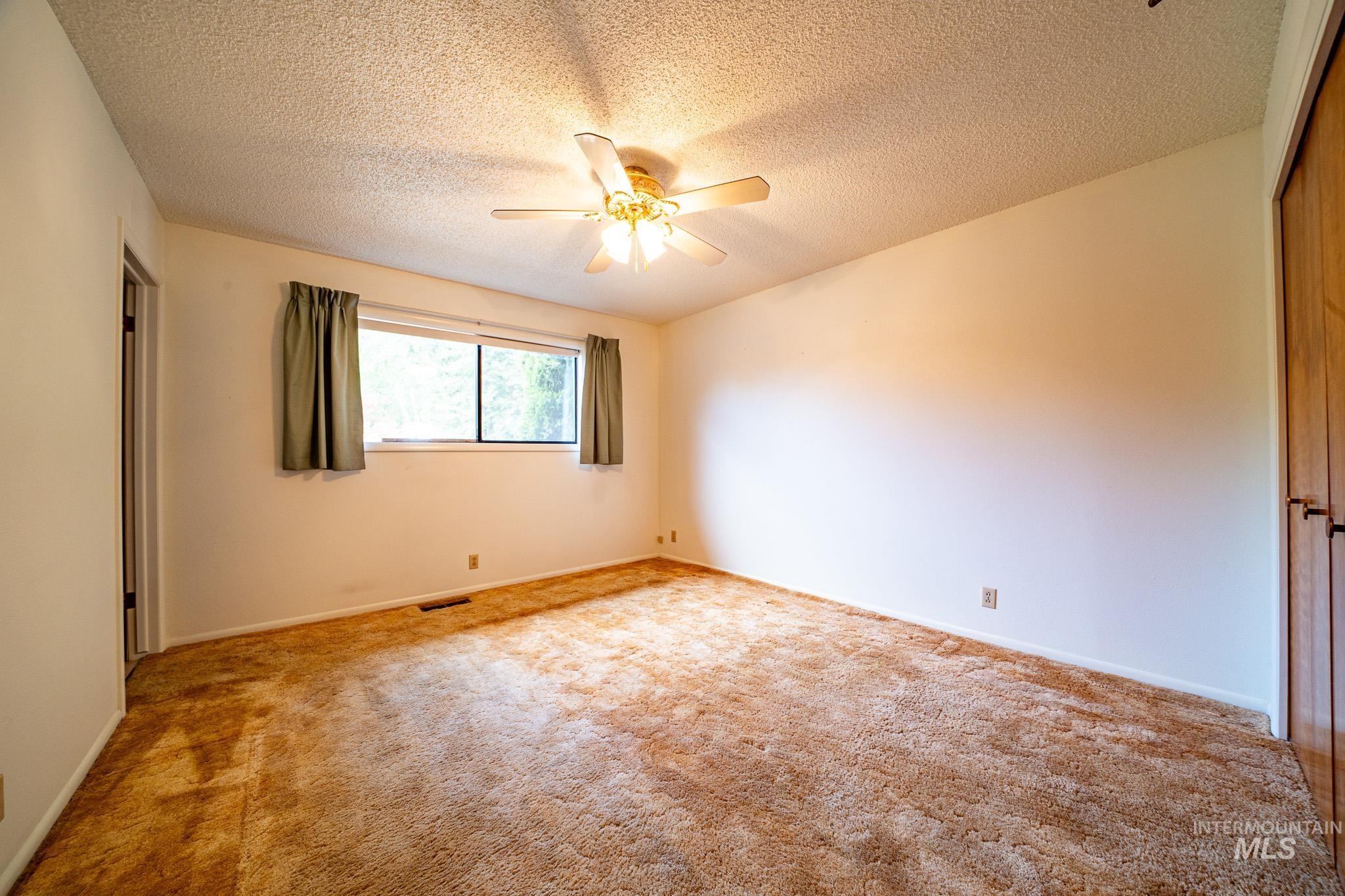 Carpeted spare room with a textured ceiling and a ceiling fan