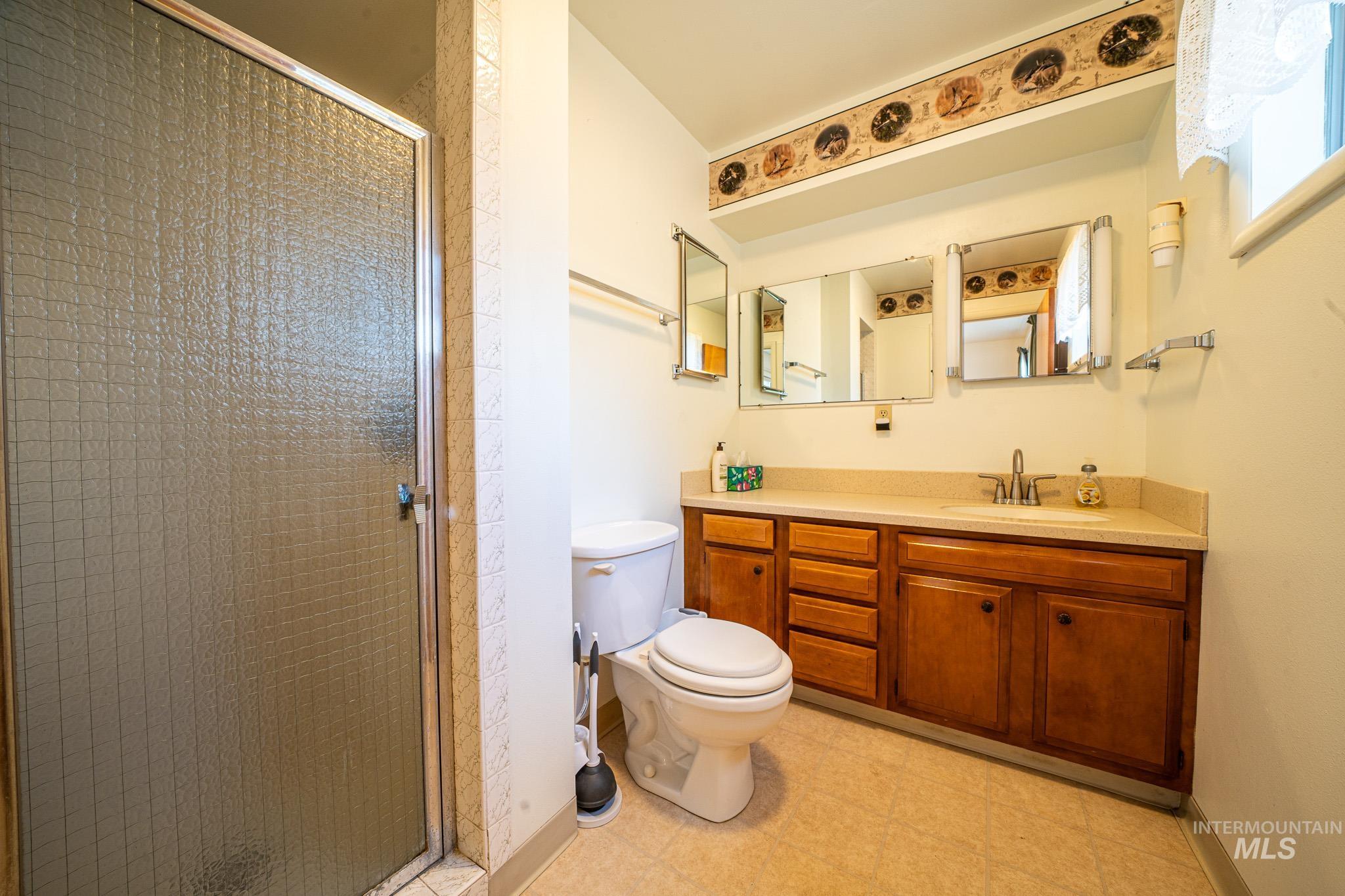 Full bath featuring a stall shower, vanity, and light flooring