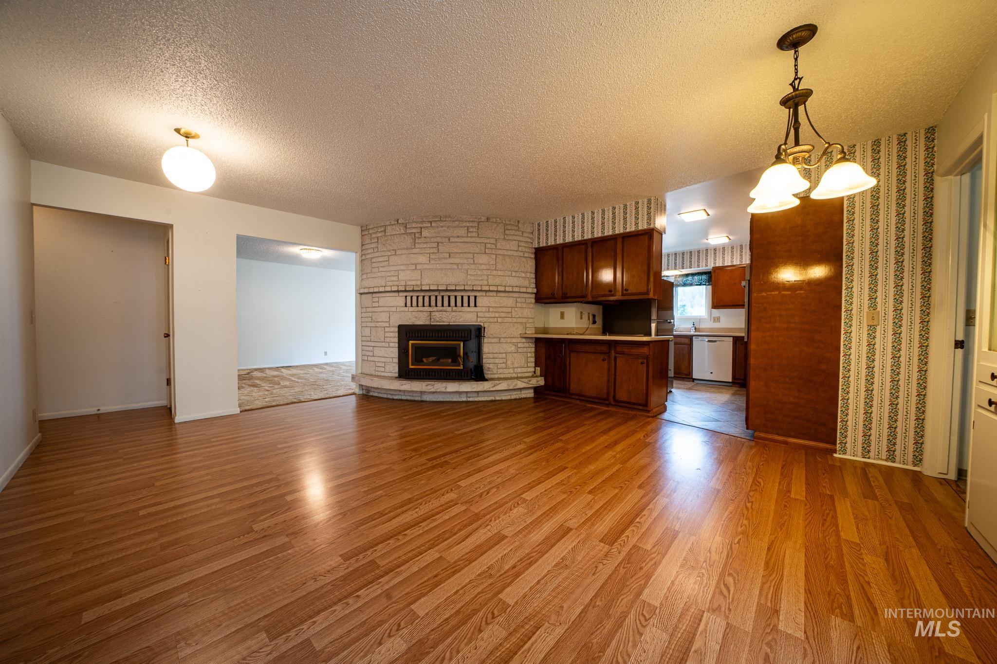 Unfurnished living room with a textured ceiling, light wood finished floors, a fireplace, and a chandelier