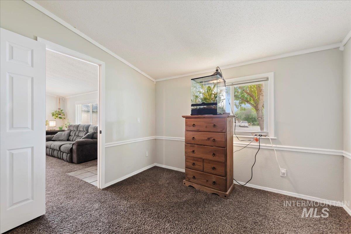 Dining space with crown molding, dark colored carpet, and a textured ceiling