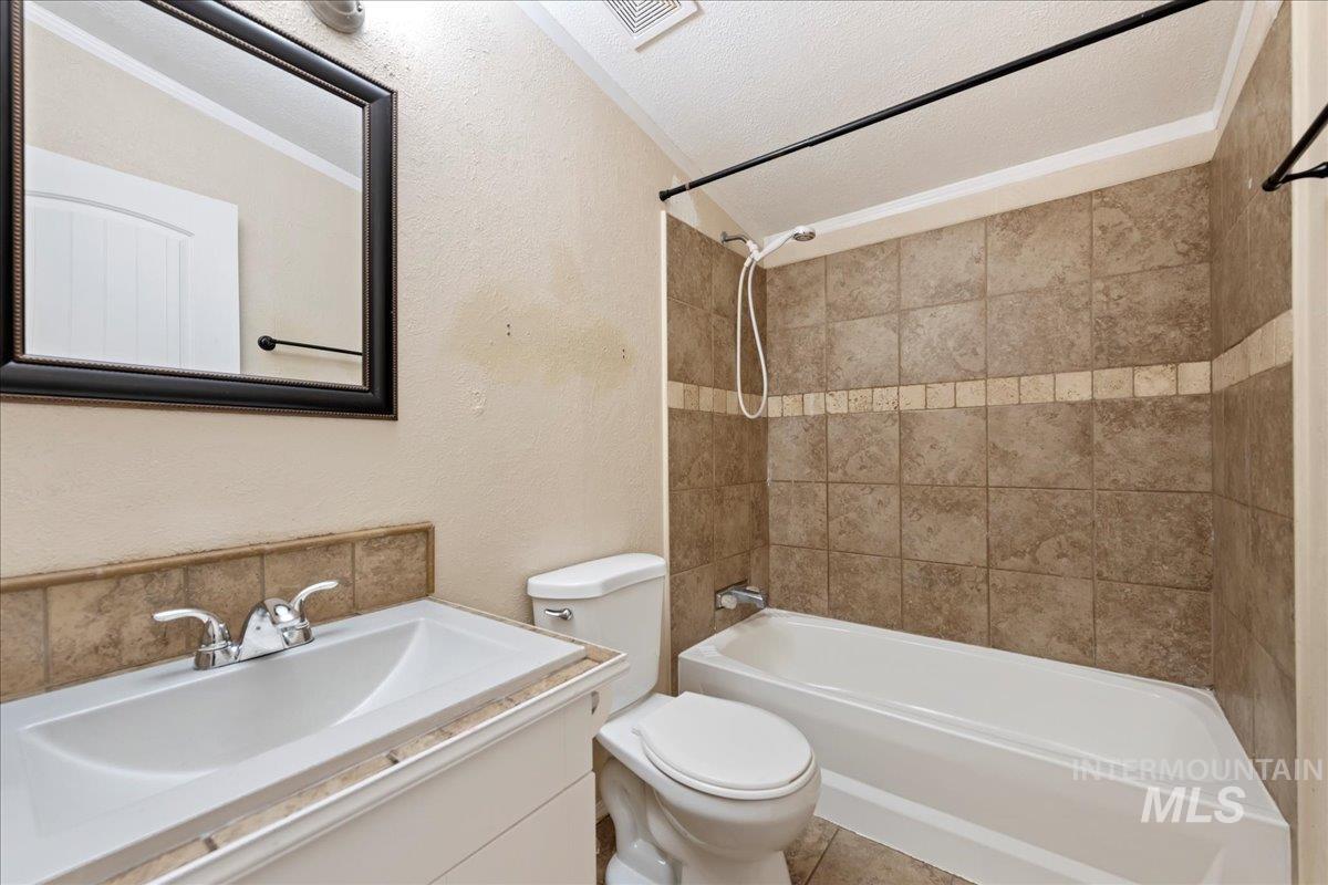Full bathroom featuring a textured wall, washtub / shower combination, vanity, and a textured ceiling
