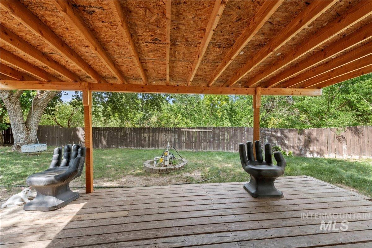 Wooden terrace with a fenced backyard and an outdoor fire pit