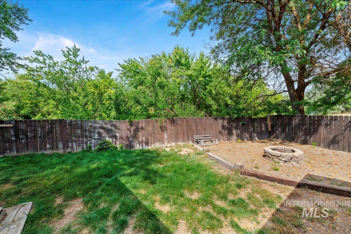 Fenced backyard with an outdoor fire pit and a patio area