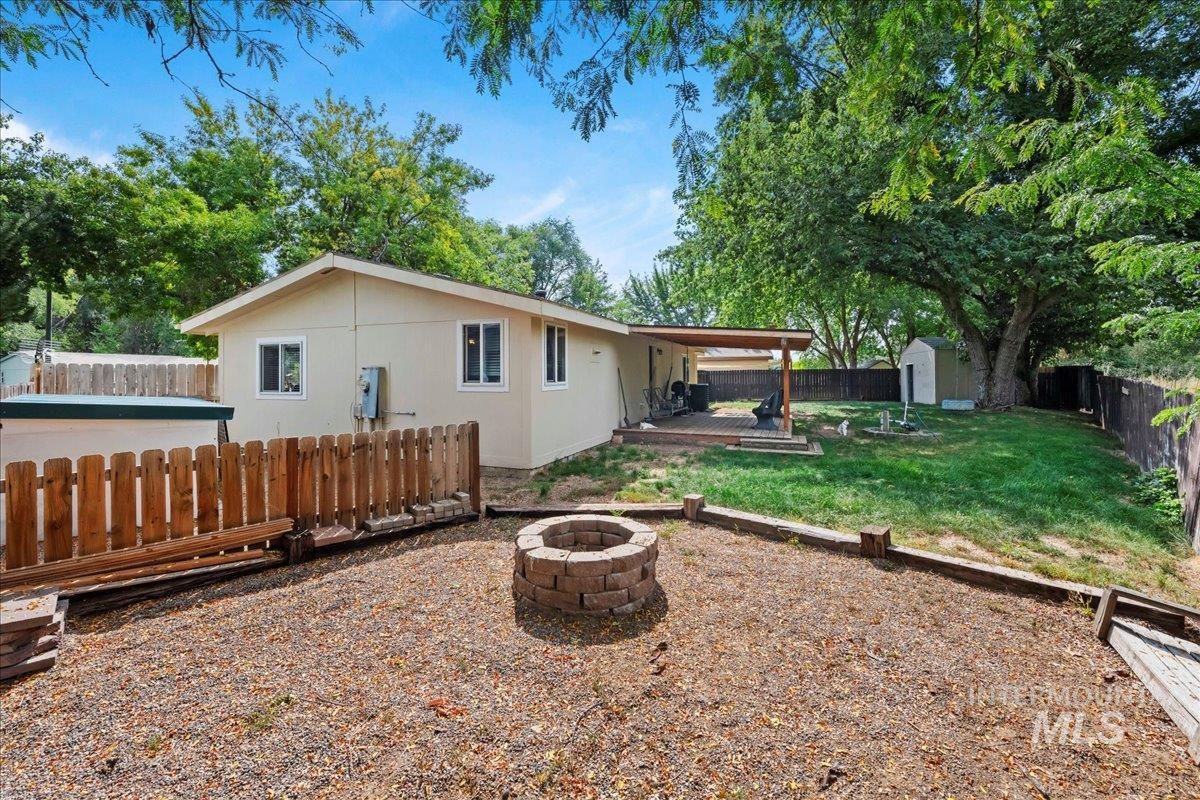Fenced backyard featuring a storage shed, a wooden deck, and a fire pit