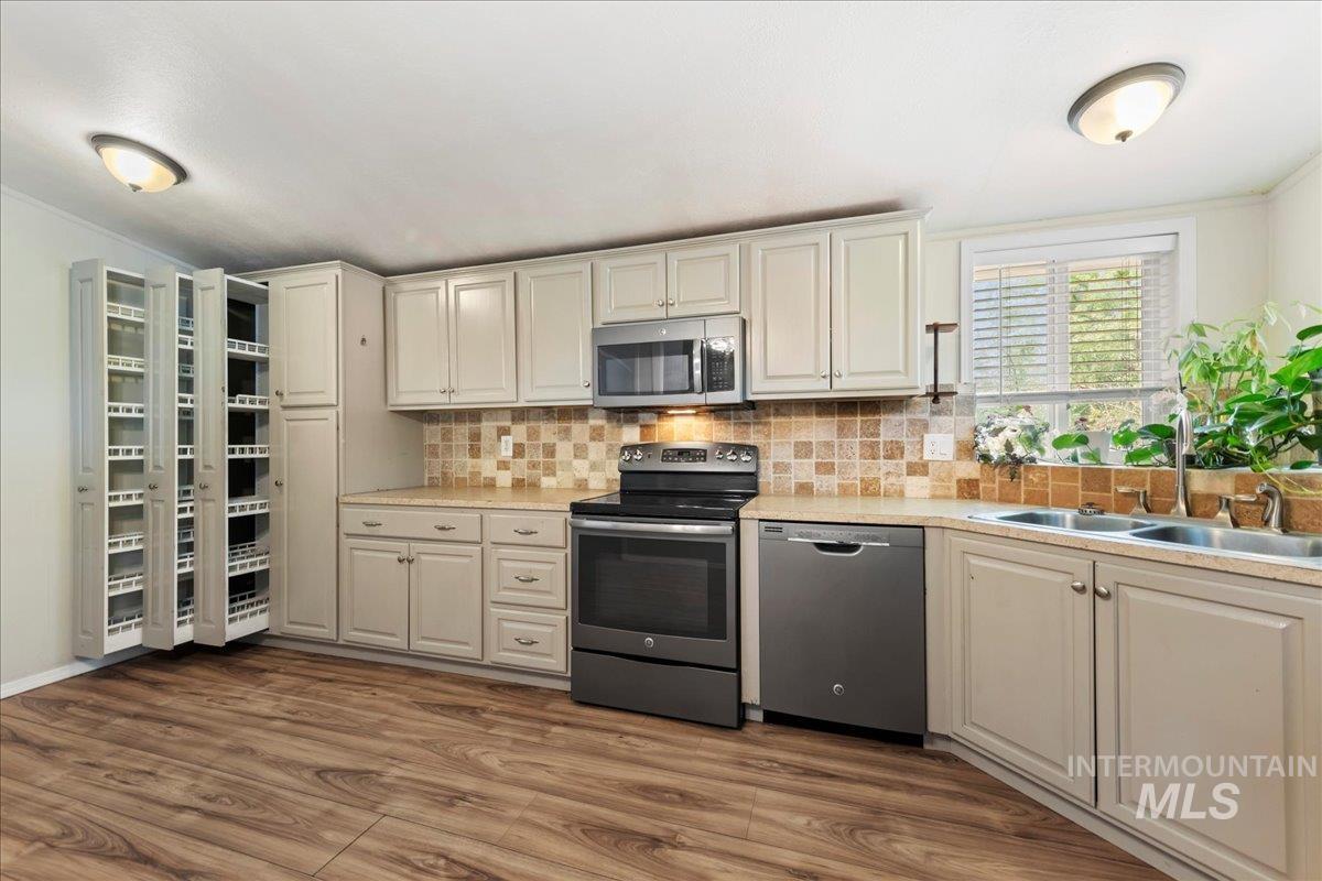 Kitchen with appliances with stainless steel finishes, tasteful backsplash, ornamental molding, and dark wood-style flooring