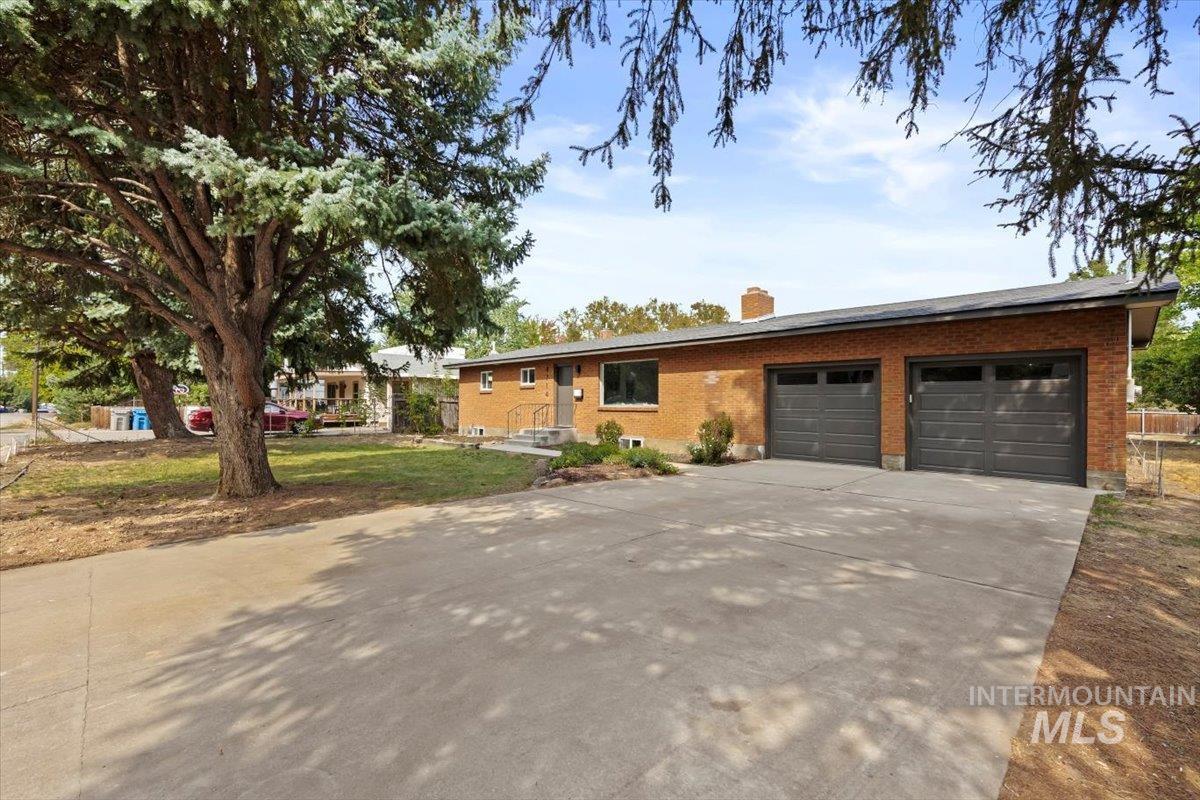 Ranch-style house featuring brick siding, concrete driveway, and a chimney