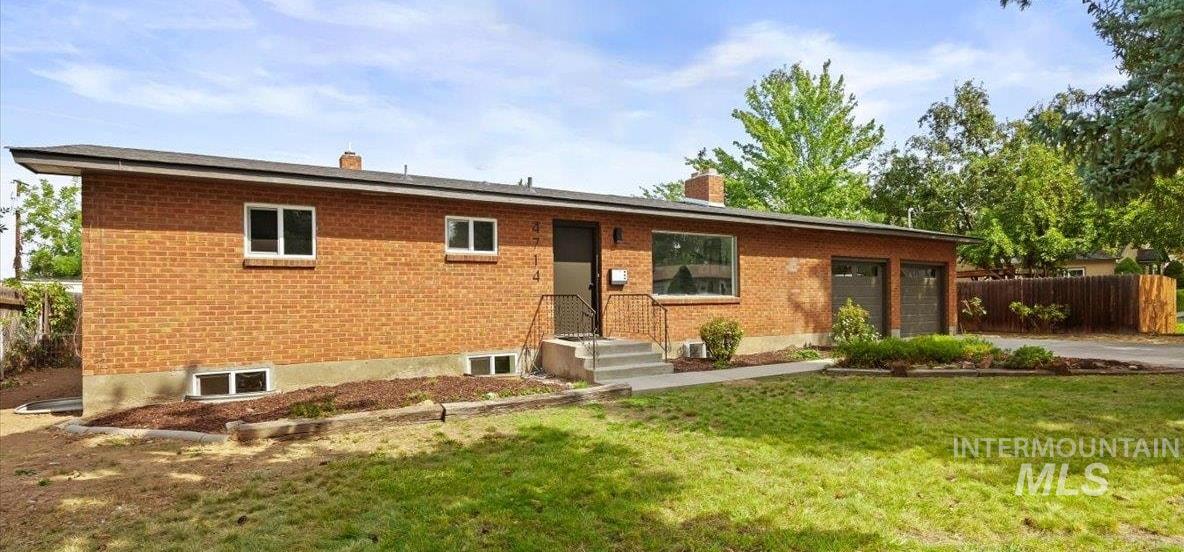Ranch-style house with a chimney, brick siding, an attached garage, and driveway