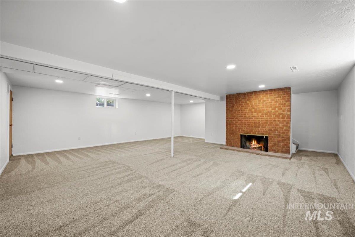 Basement with a fireplace, light carpet, and recessed lighting