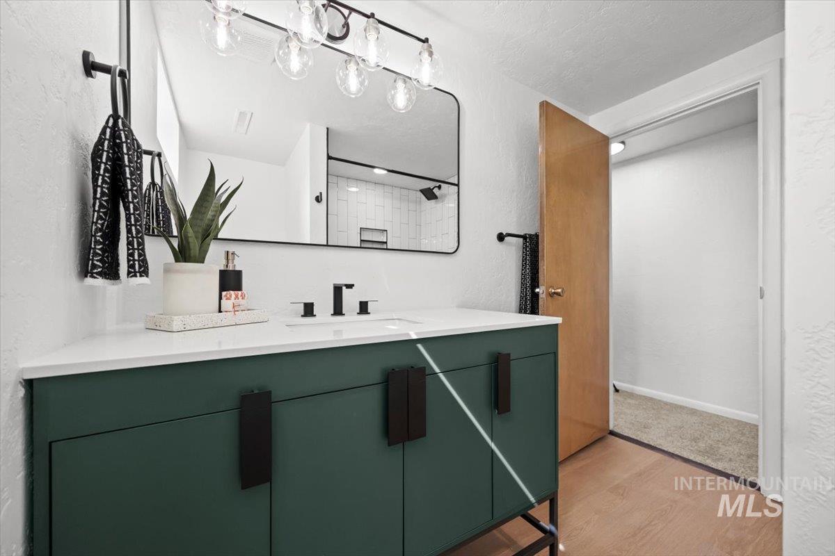 Bathroom with a textured wall, vanity, light wood finished floors, and a textured ceiling