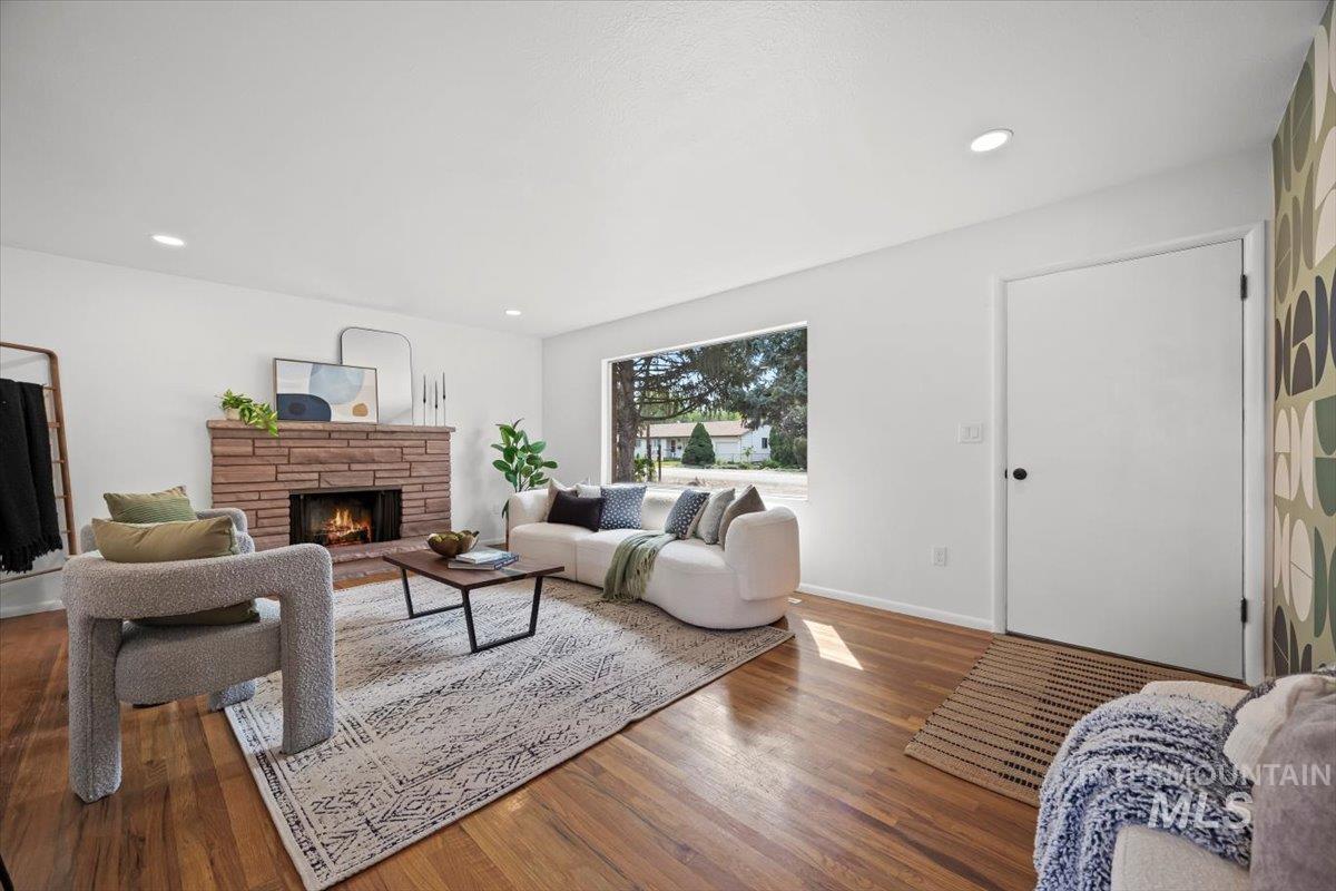 Living room with a stone fireplace, wood finished floors, and recessed lighting