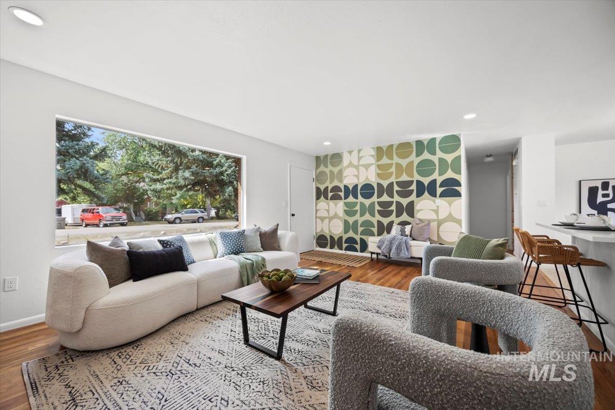 Living room with recessed lighting, wood finished floors, and an accent wall