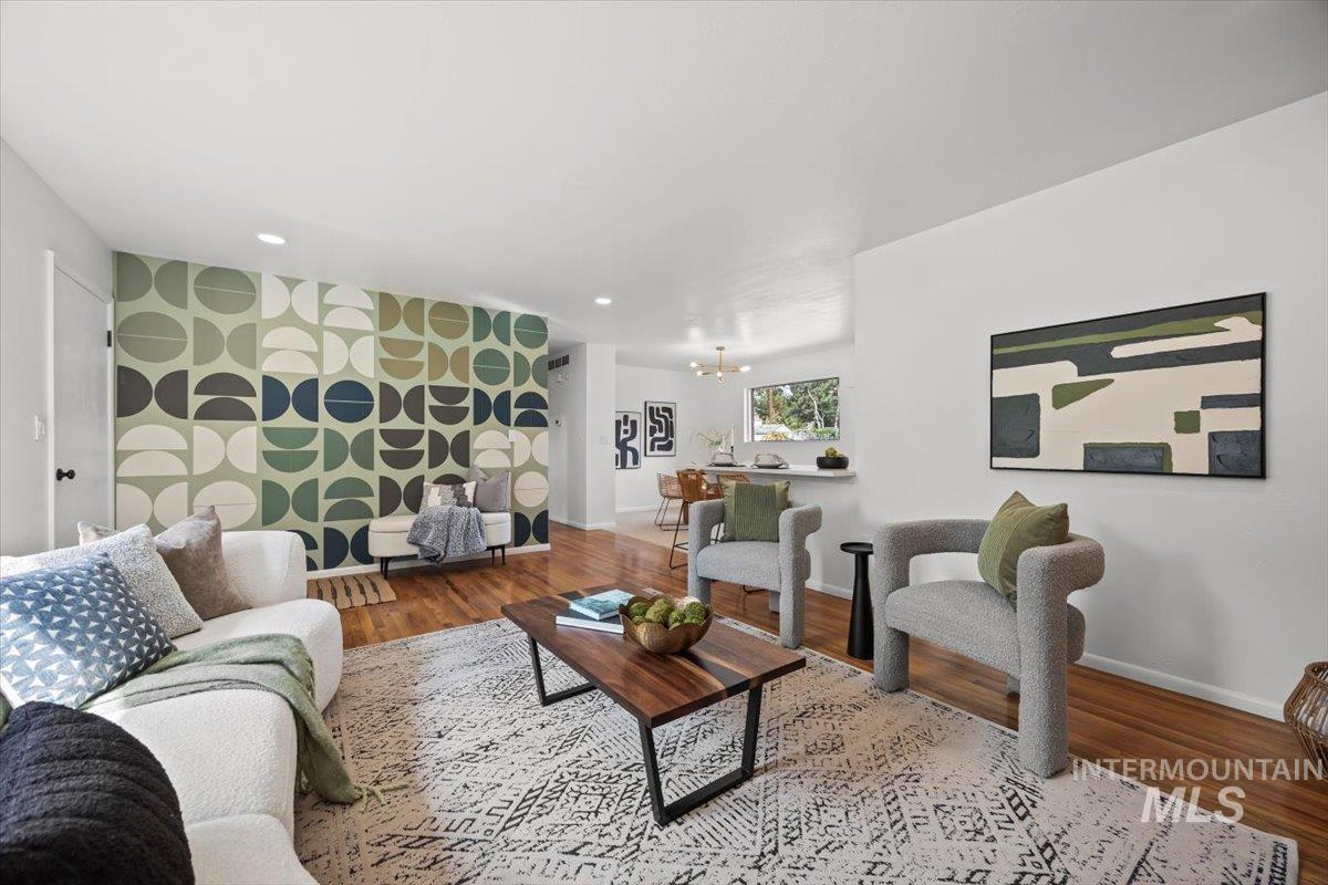 Living area featuring an accent wall, wood finished floors, a chandelier, wallpapered walls, and recessed lighting