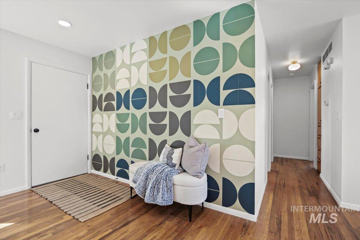 Sitting room featuring an accent wall, wood finished floors, wallpapered walls, and recessed lighting