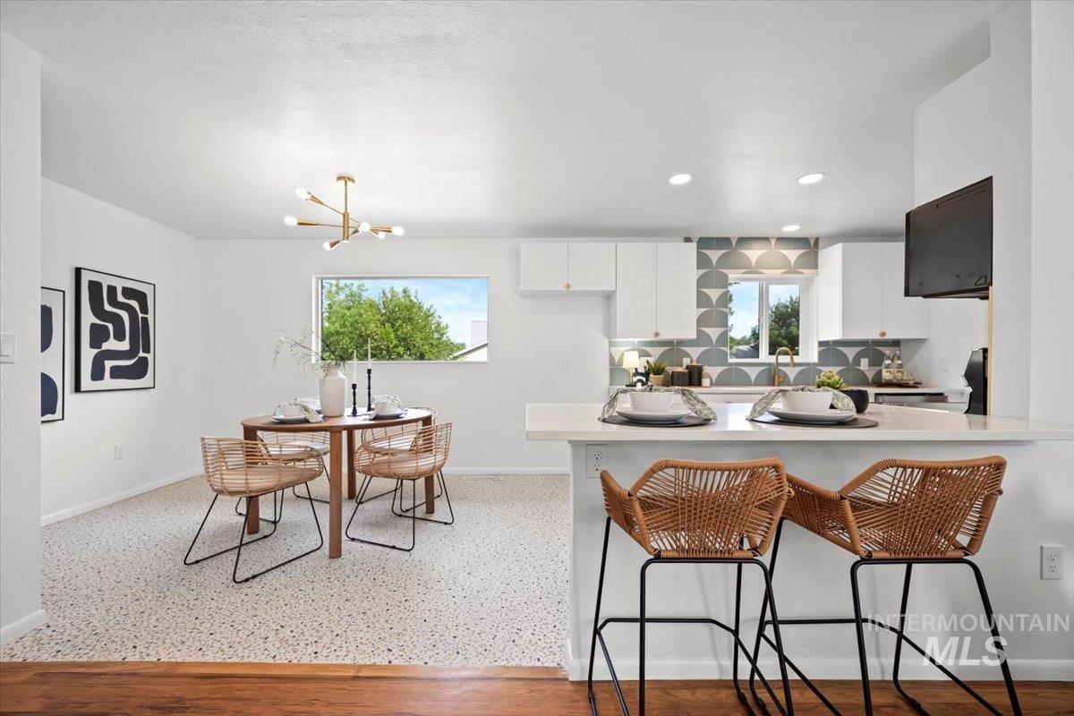 Kitchen featuring white cabinetry, a breakfast bar area, light countertops, stove, and a peninsula