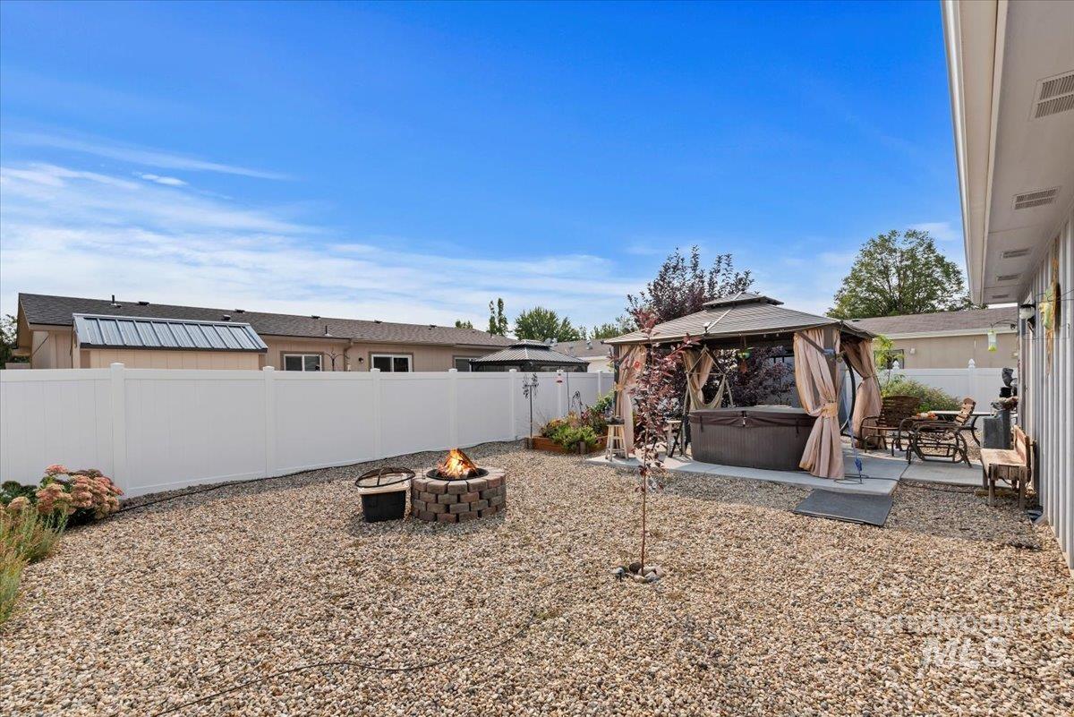 Fenced backyard featuring a gazebo, a patio, a hot tub, and an outdoor fire pit