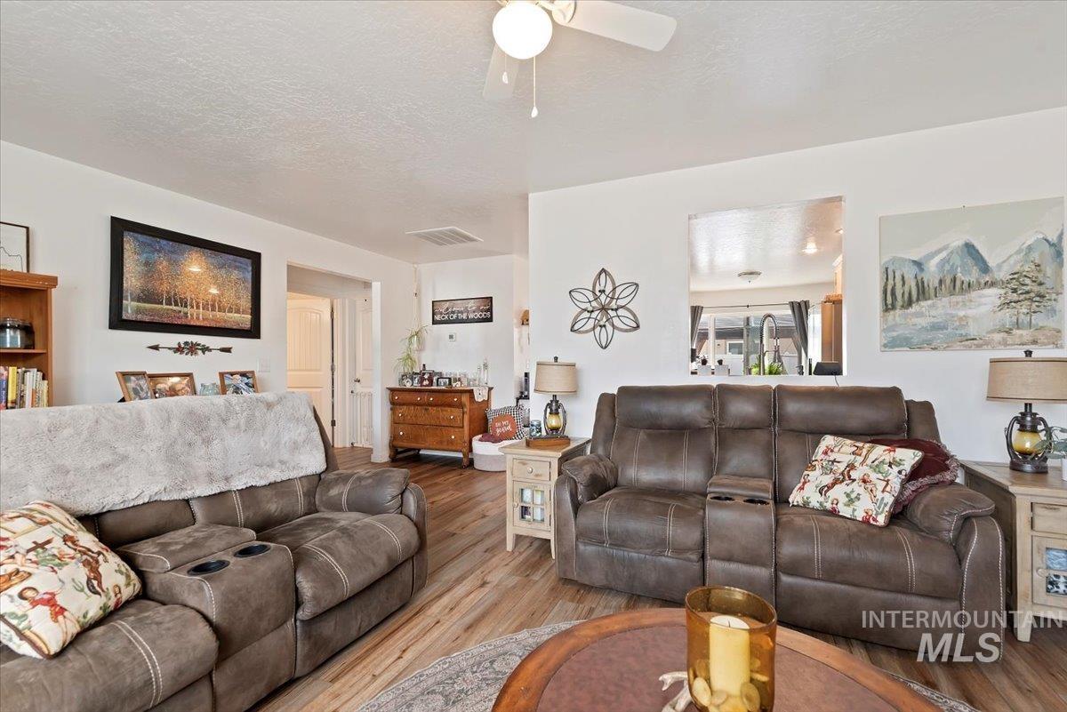 Living area with a textured ceiling, wood finished floors, and a ceiling fan