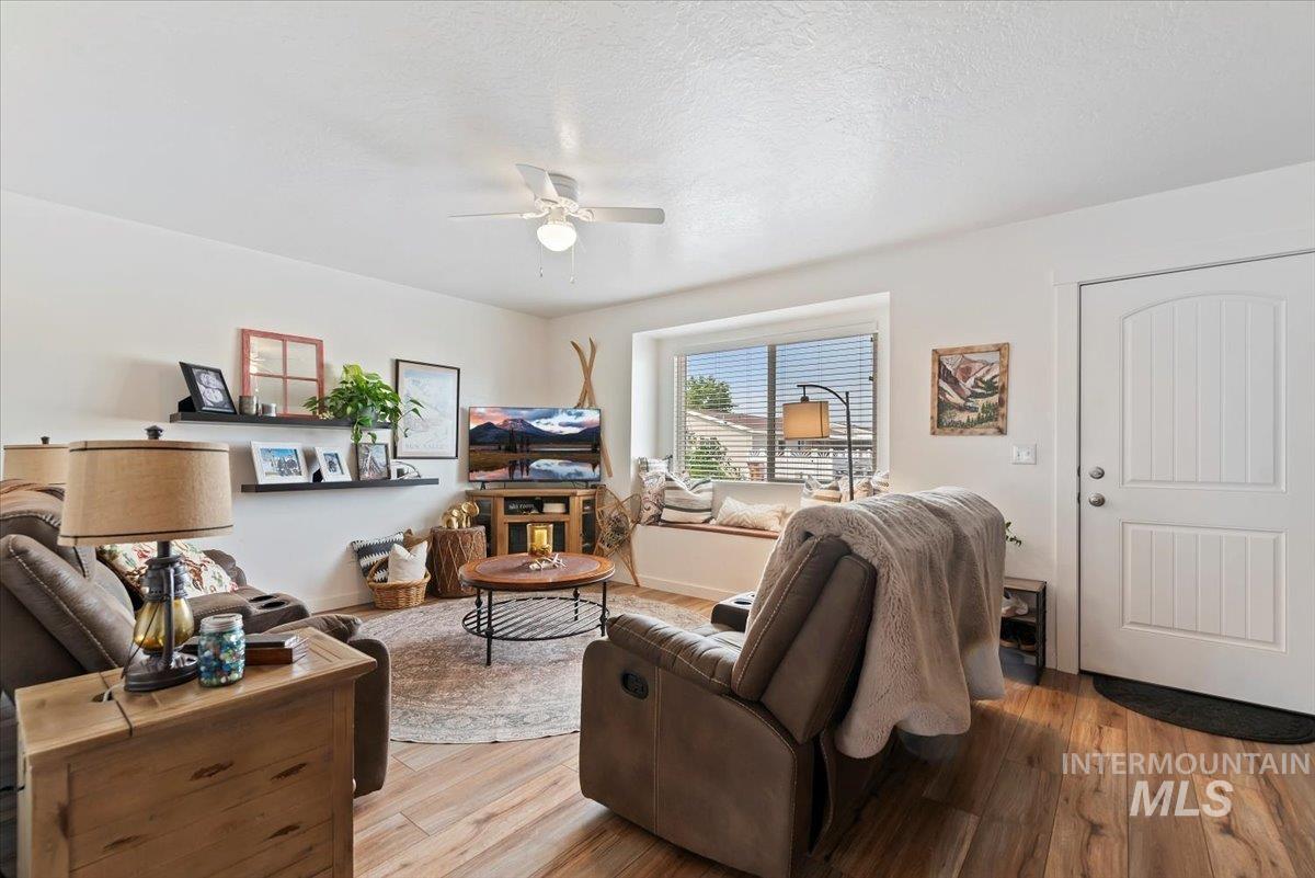 Living room featuring a textured ceiling, wood finished floors, and ceiling fan