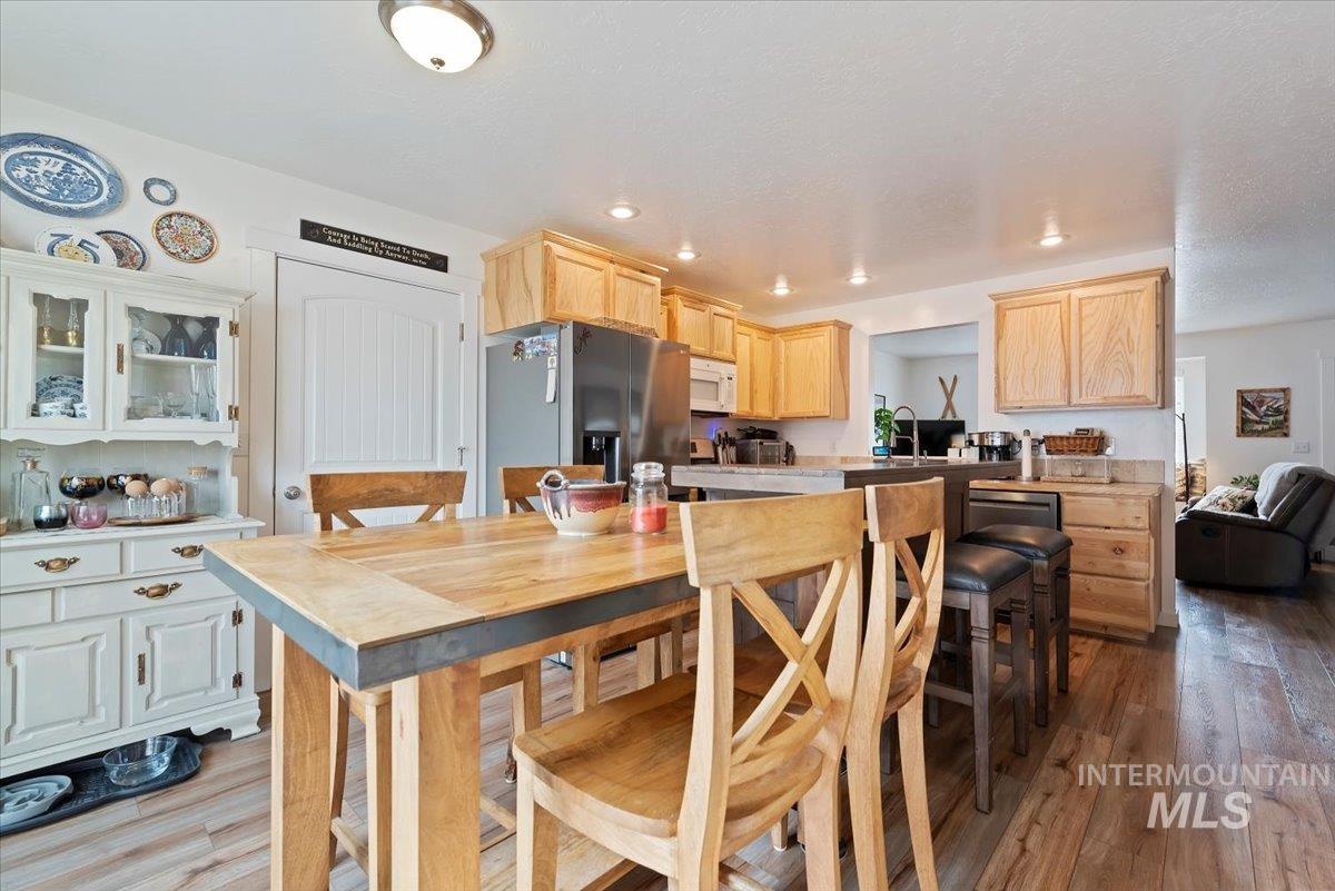 Kitchen featuring light brown cabinetry, stainless steel fridge with ice dispenser, light wood-style flooring, light countertops, and white microwave