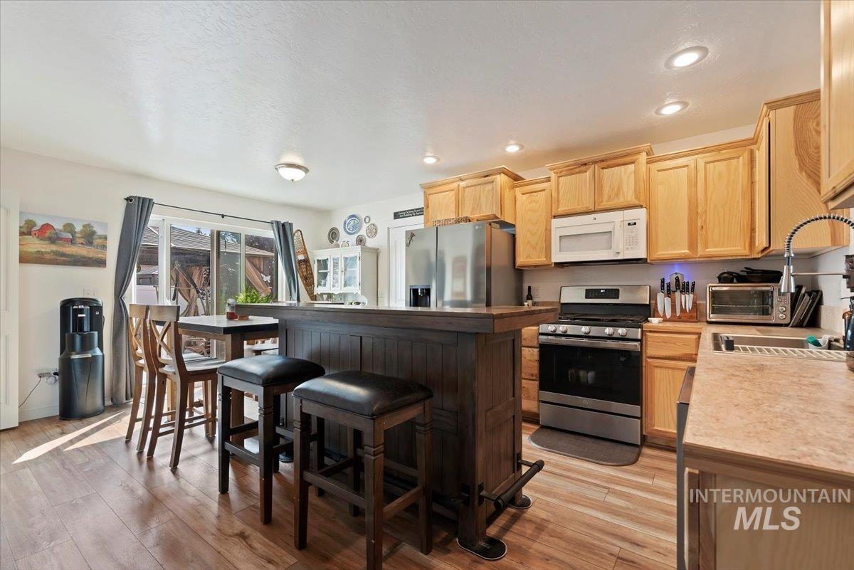 Kitchen with light brown cabinetry, stainless steel appliances, recessed lighting, light wood-type flooring, and light countertops