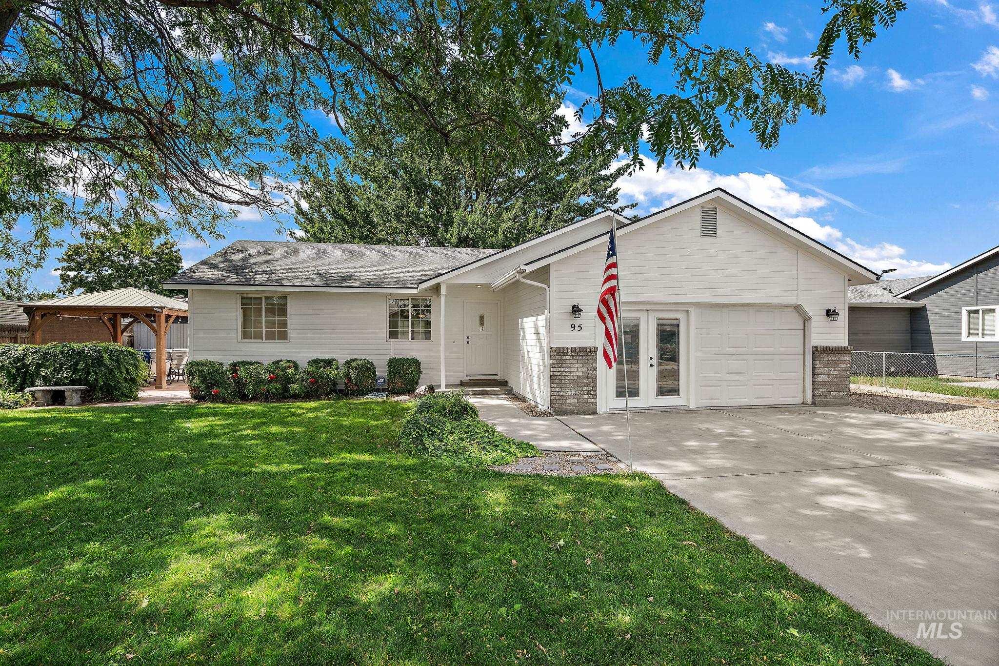 Single story home with a gazebo, driveway, a patio area, an attached garage, and brick siding