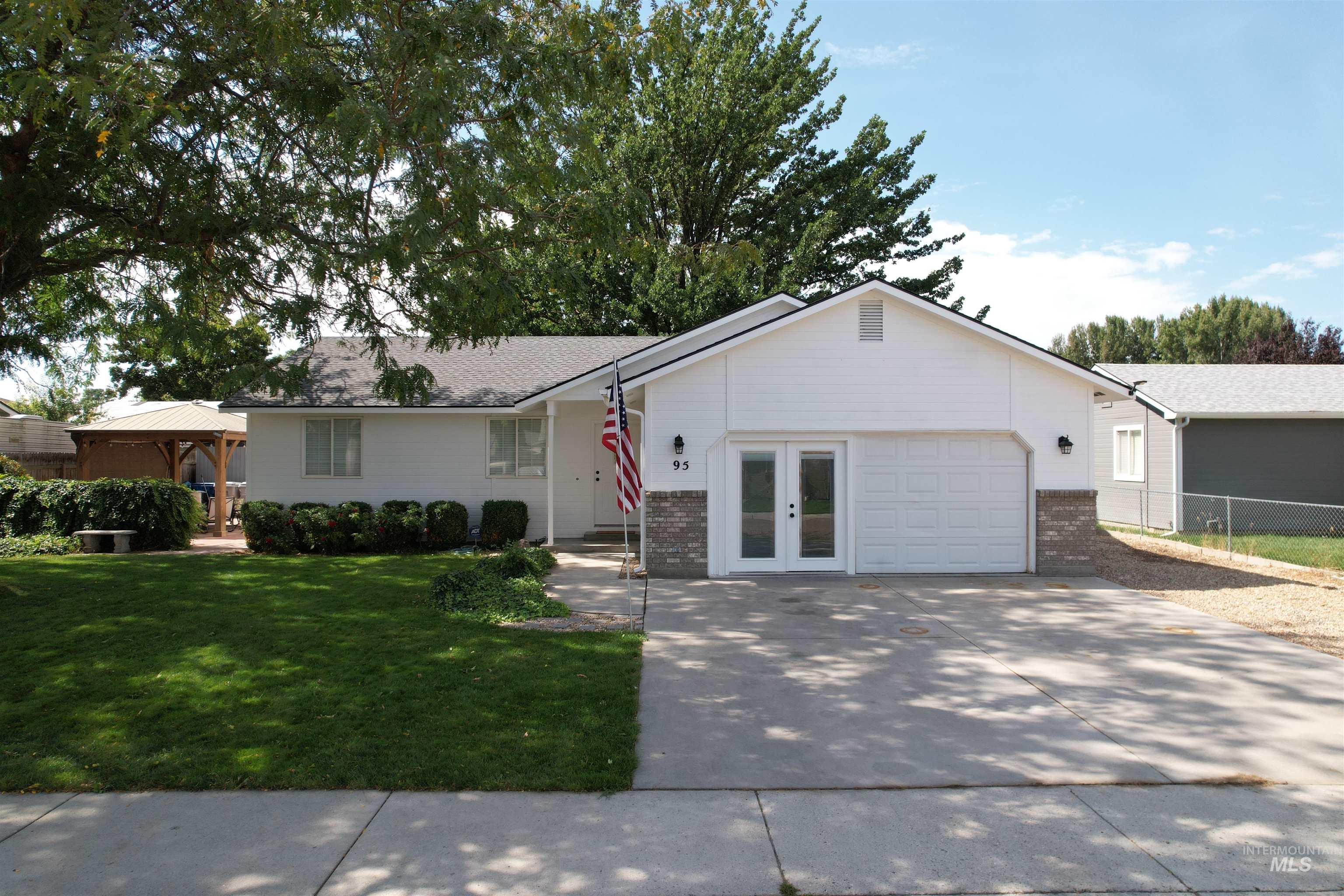 Single story home featuring brick siding, driveway, a gazebo, and an attached garage