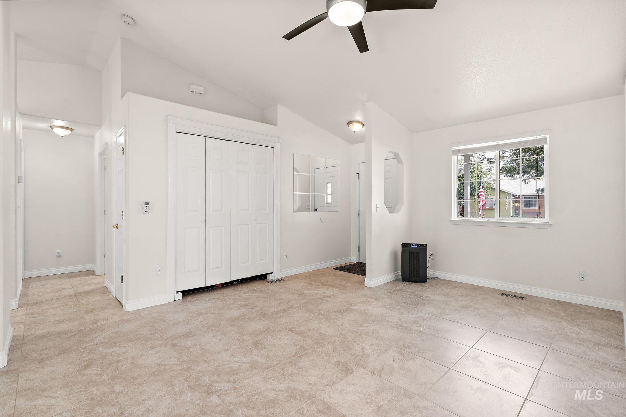 Unfurnished bedroom featuring vaulted ceiling, ceiling fan, a closet, and light tile patterned flooring