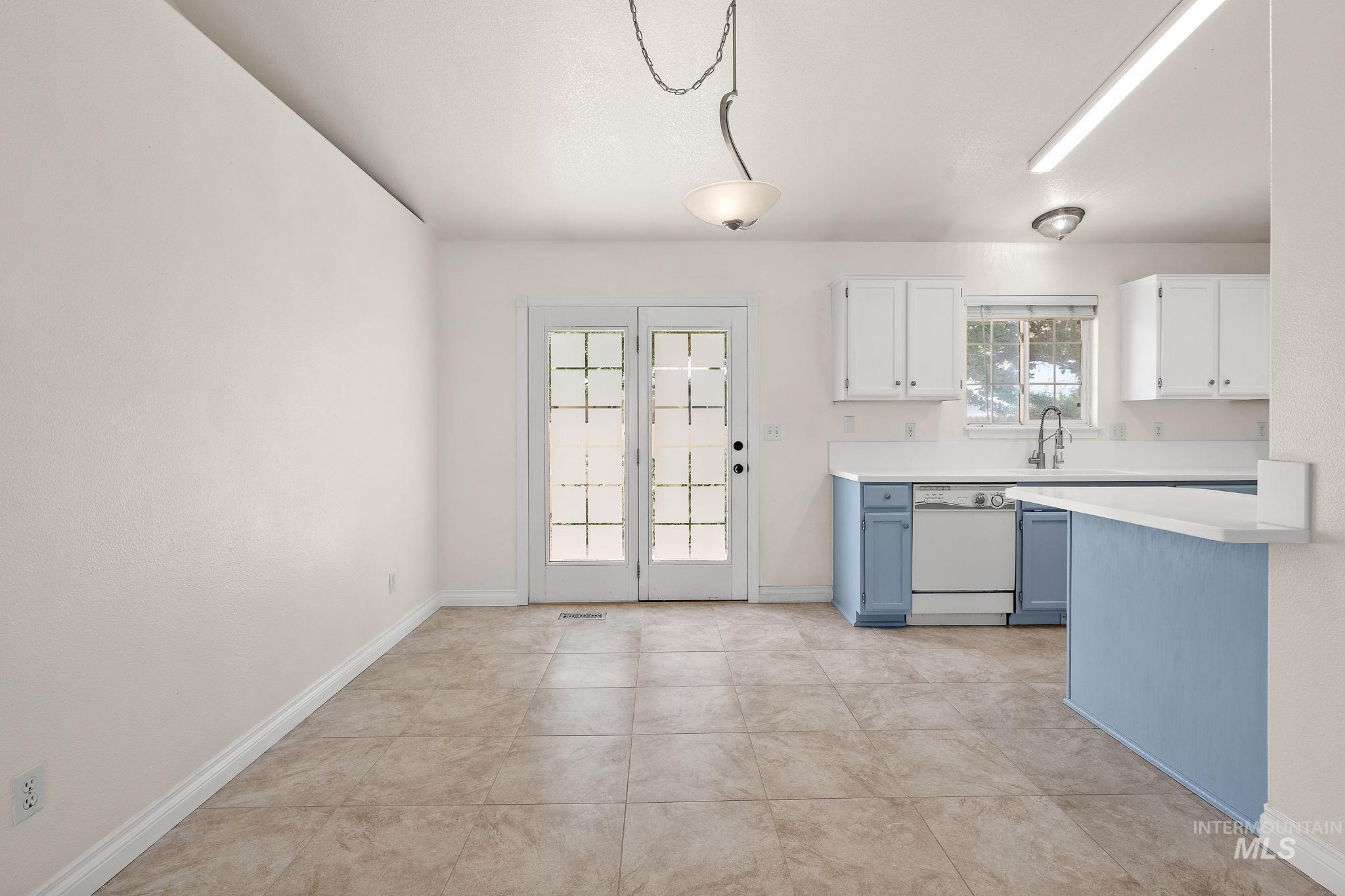 Kitchen with blue cabinetry, white cabinetry, light countertops, dishwasher, and light tile patterned flooring
