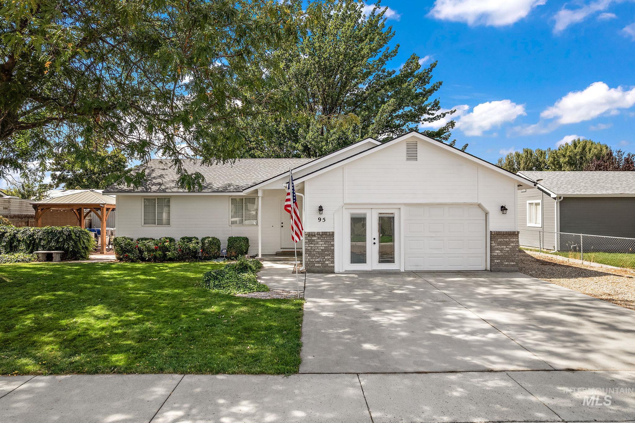 Ranch-style home featuring brick siding, concrete driveway, a gazebo, and a garage