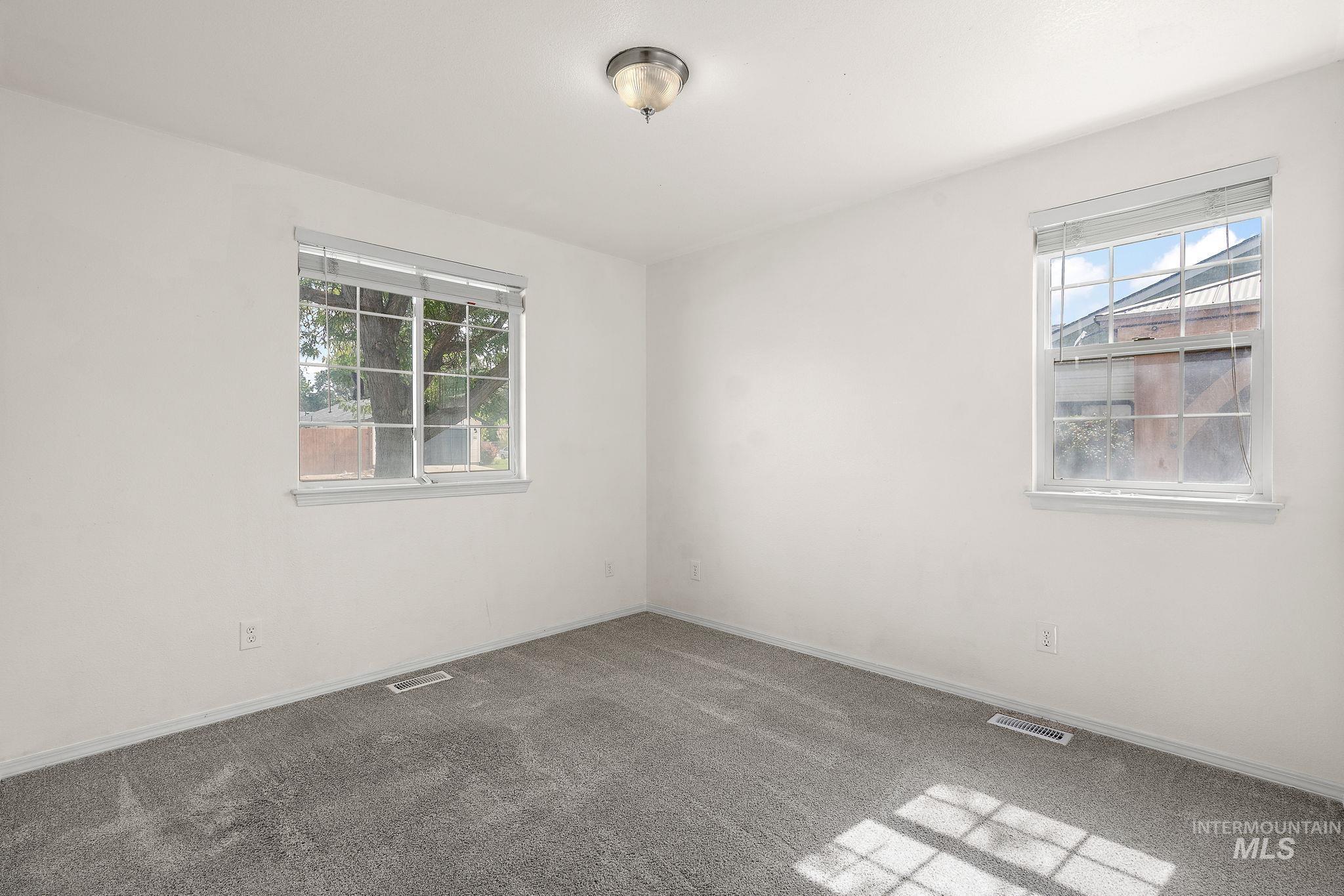 Spare room featuring carpet flooring and baseboards