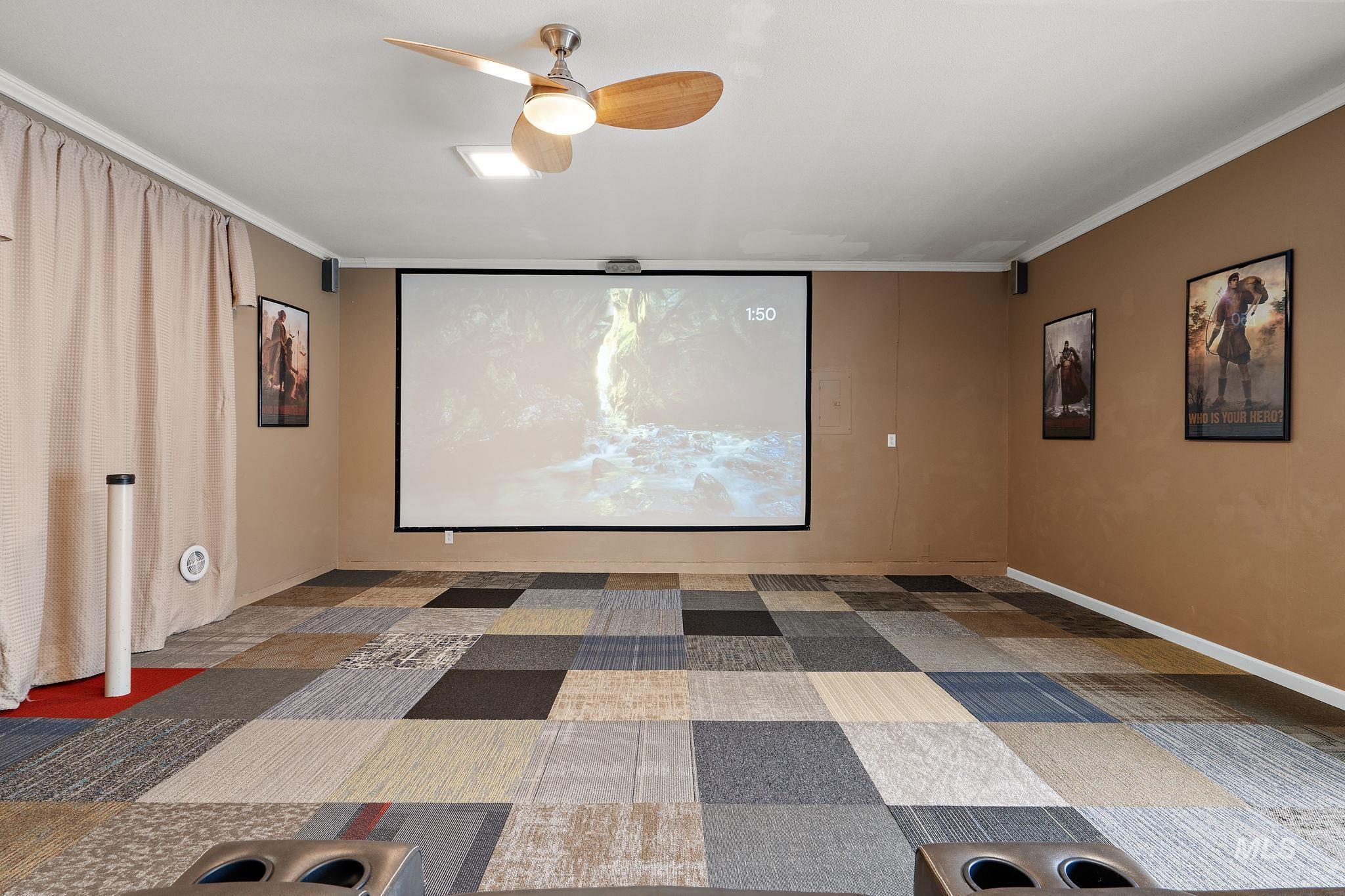 Home theater with ornamental molding, light carpet, and a ceiling fan