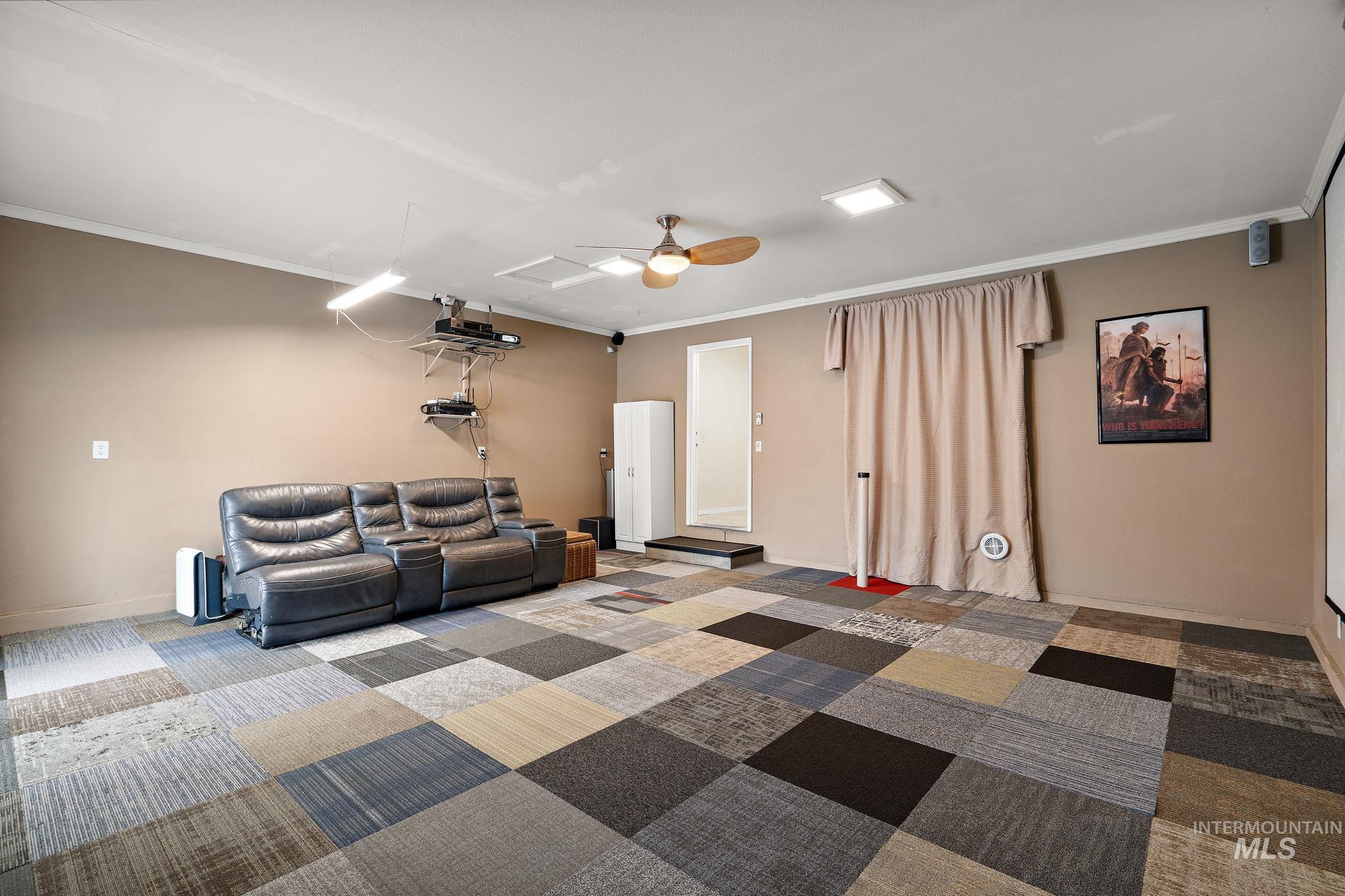 Home theater featuring ornamental molding, carpet floors, and a ceiling fan