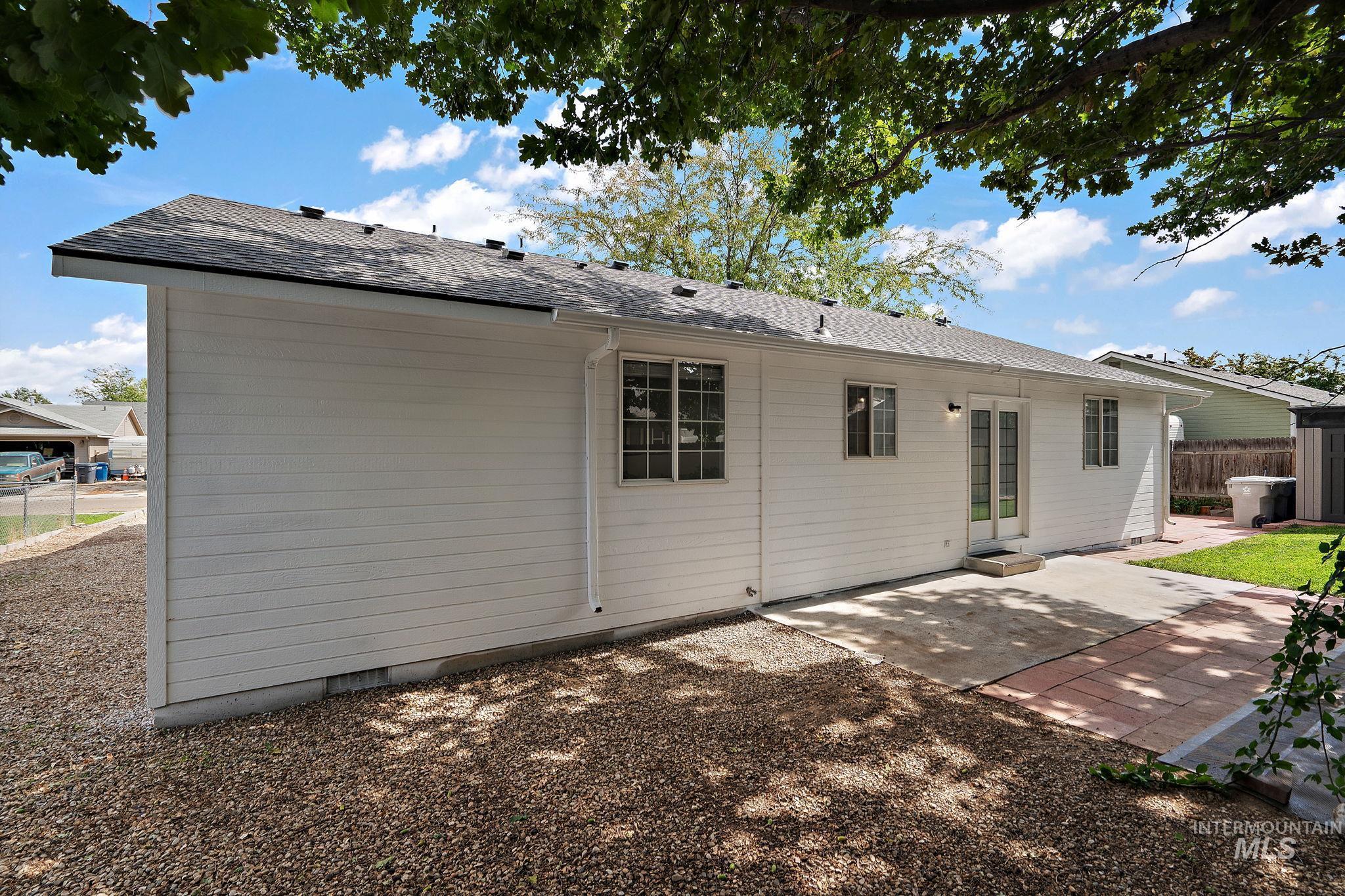 Rear view of property featuring a patio area, a shingled roof, and crawl space